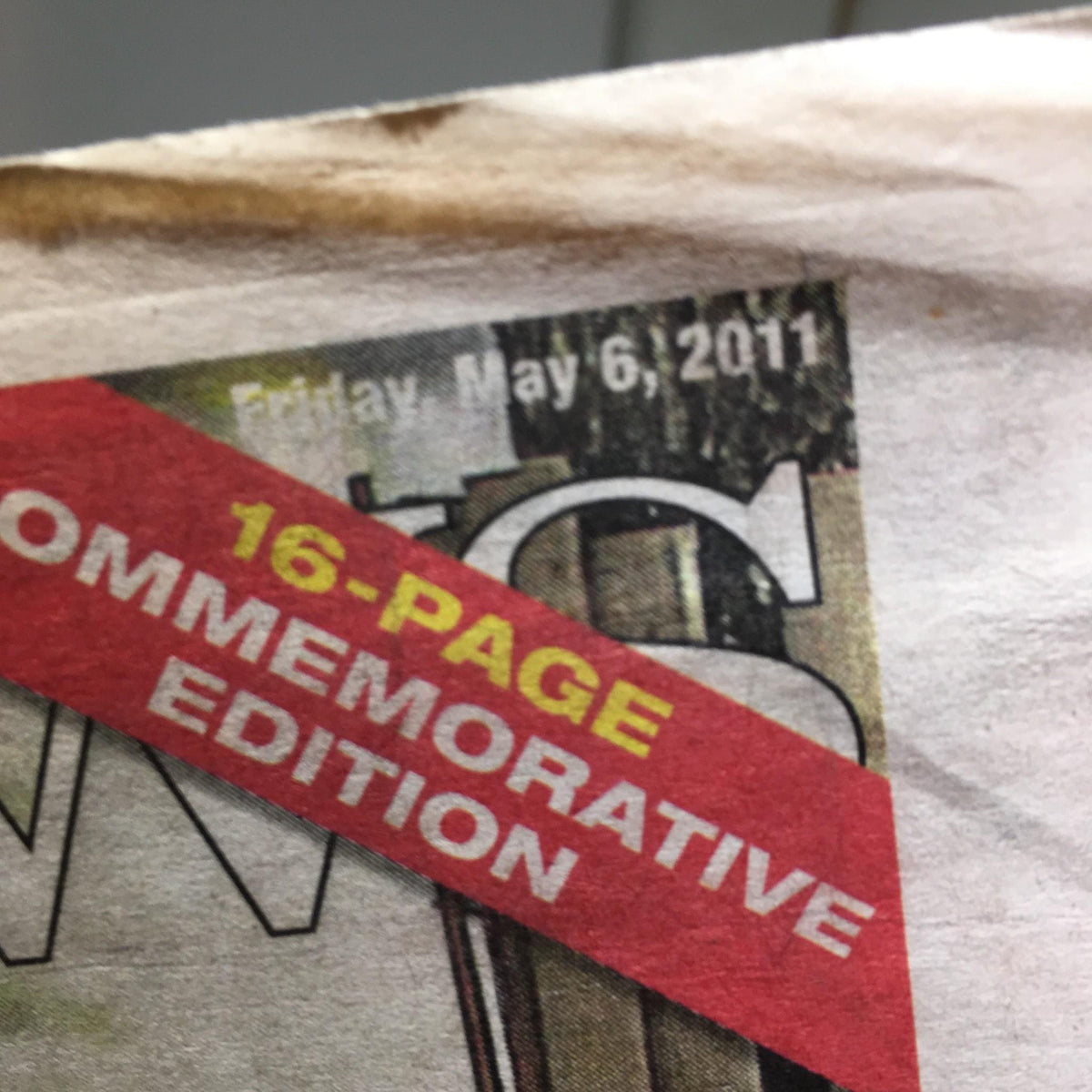 Close-up of NY Daily News dated May 6, 2011, featuring a banner stating '16-page commemorative edition' emphasizing the significance of Obama's visit to Ground Zero.