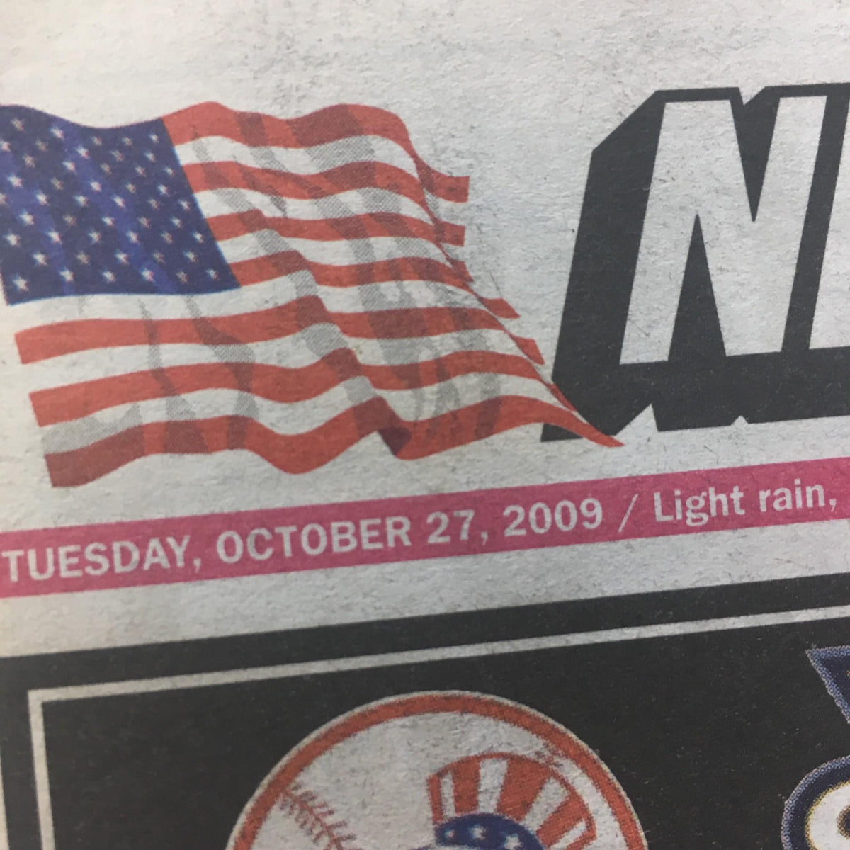 Close-up of the New York Post dated October 27, 2009, showing the date, 'TUESDAY, OCTOBER 27, 2009,' and weather condition 'Light rain,' above an American flag graphic.