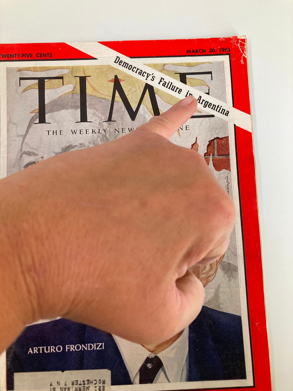 Close-up of the cover of VTG Time Magazine March 30 1962, with a hand pointing to the headline 'Democracy's Failure in Argentina' and the name Arturo Frondizi.