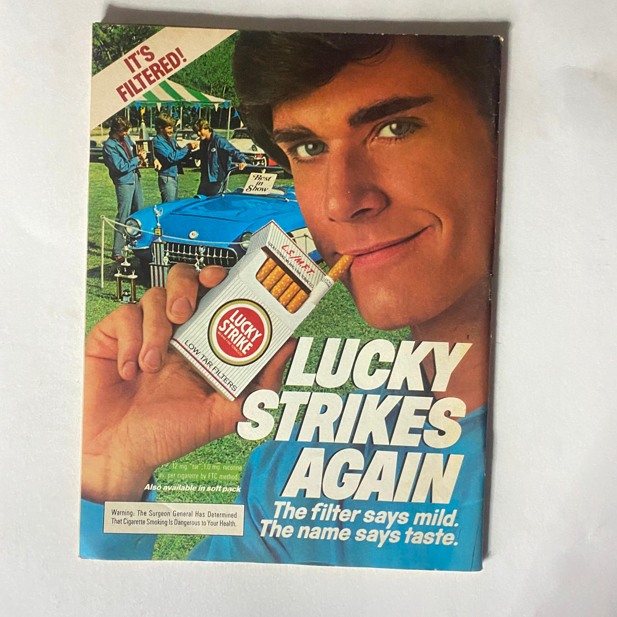 Advertisement for Lucky Strike cigarettes from the 1970s, depicting a young man enjoying a cigarette with the tagline 'Lucky Strikes Again'.