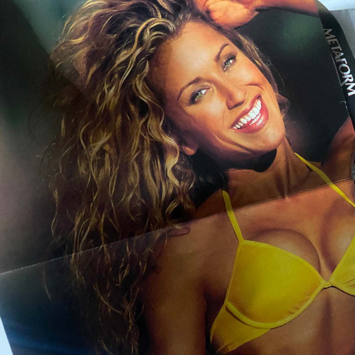 Poster of Minna Lessig in a yellow bikini featured in Muscle & Fitness Magazine April 2000, showcasing fitness beauty.