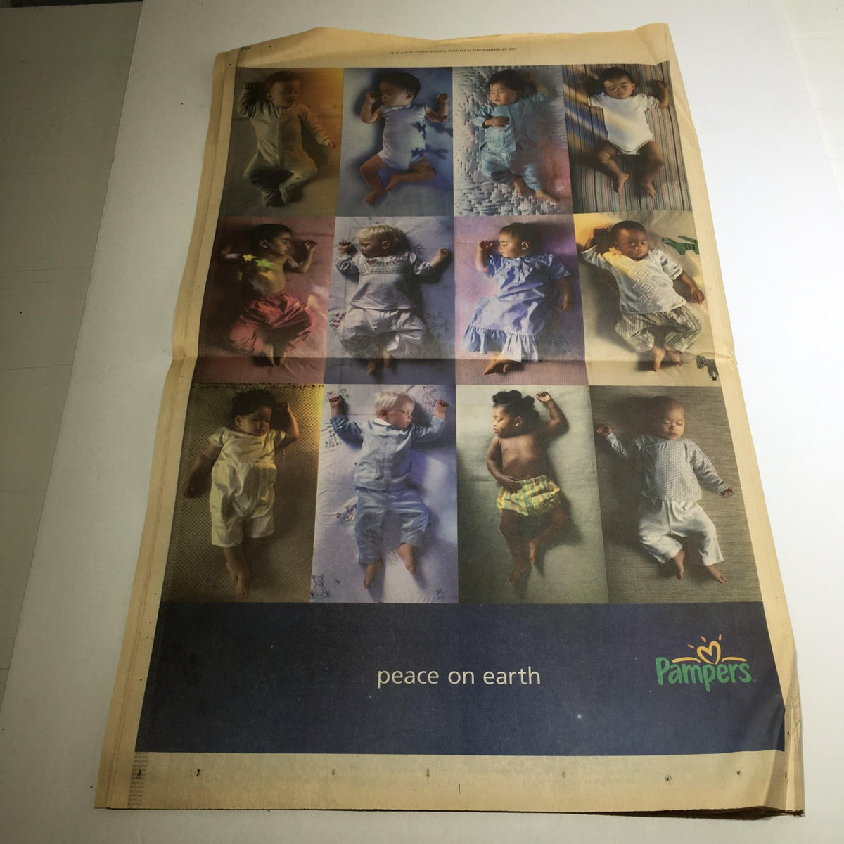 The New York Times: Dec 27 2004, 2004 The Year in Pictures, featuring an advertisement for Pampers with portraits of infants in various outfits, promoting peace on earth.