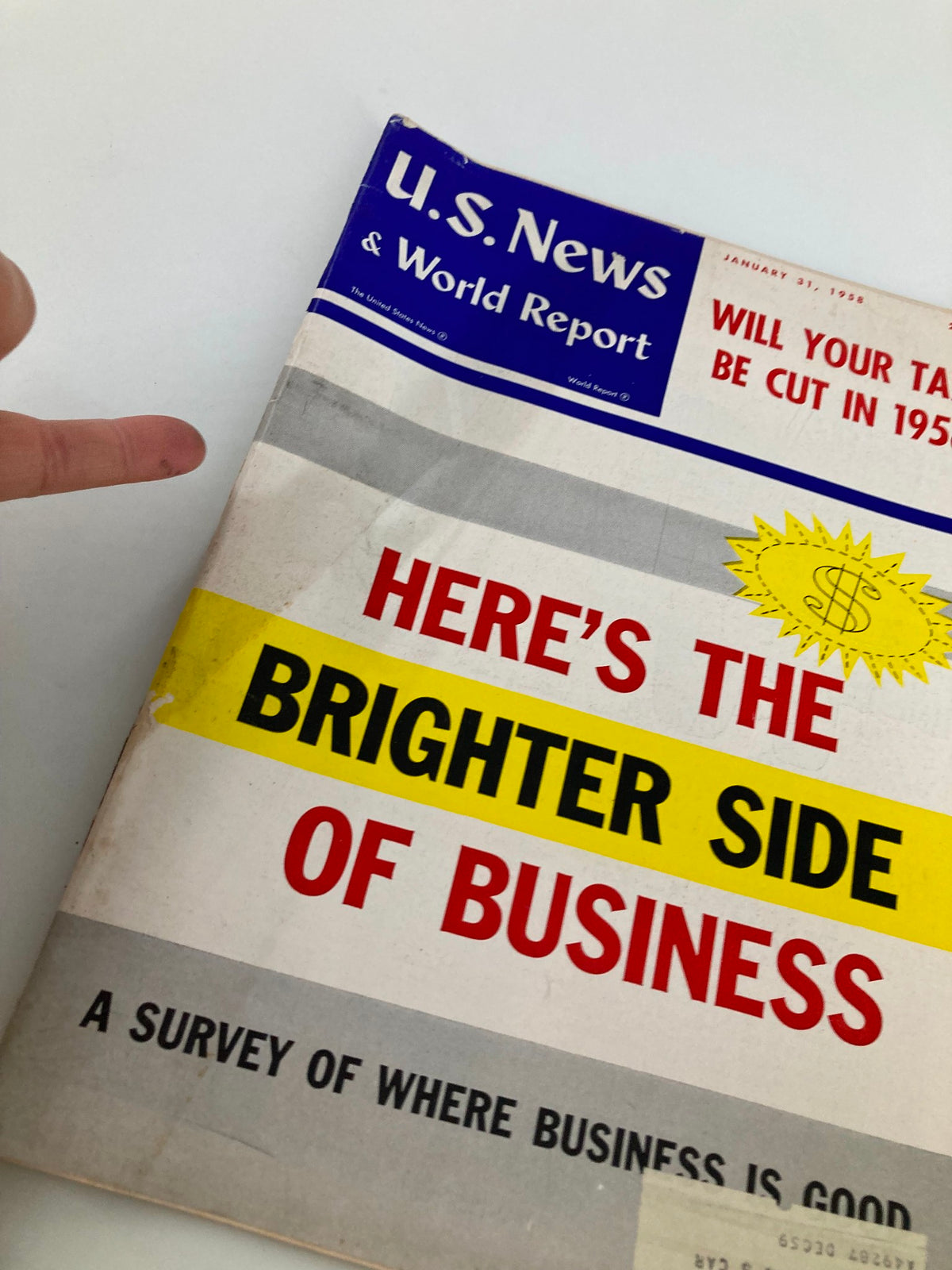 Close-up of the US News & World Report Magazine January 31 1958 cover showing the title 'Will Your Taxes Be Cut in 1958?' with a finger pointing at the highlighted text 'Here's the Brighter Side of Business'.