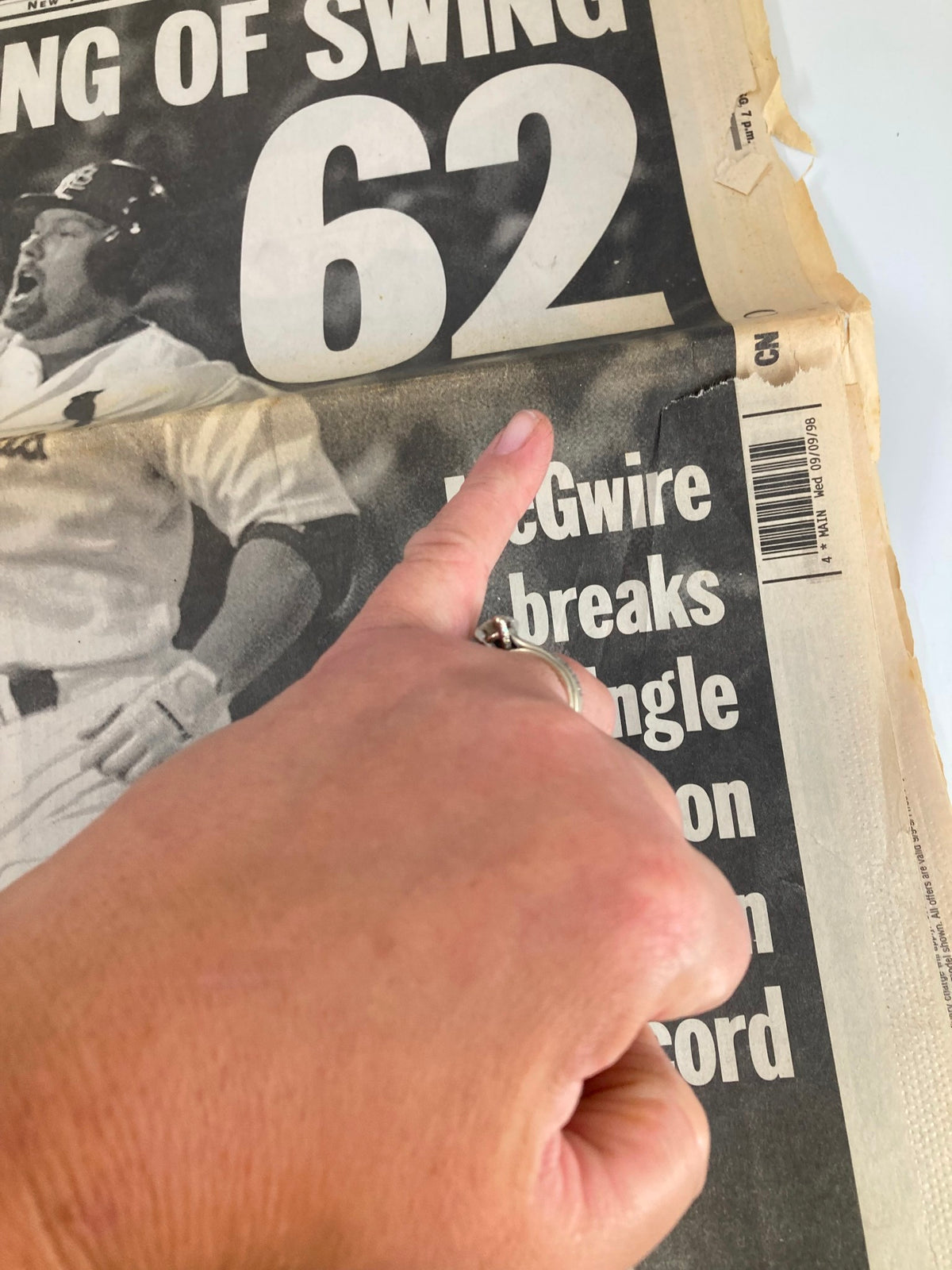 Close-up of Daily News Newspaper highlighting the headline 'KING OF SWING 62' related to Mark McGwire's achievement of breaking the single season home run record on September 8, 1998, with a hand pointing at the text.