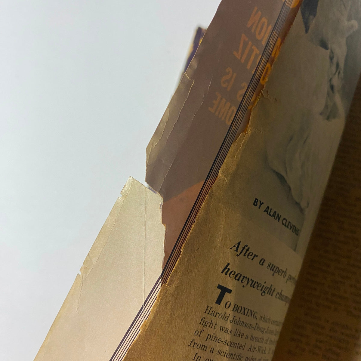 Close-up of the edge of the Boxing Illustrated Magazine August 1962, featuring Carlos Ortiz on the cover, showing wear and damage. This magazine is a vintage collectible valued for its historical significance in boxing.