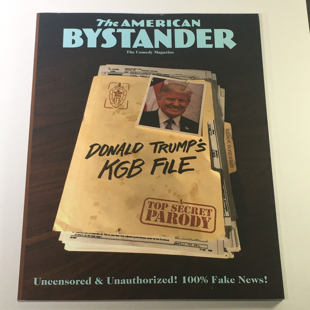Cover of The Comedy Magazine 7th American Bystander 2019 featuring Pres. Donald Trump's KGB File, labeled 'Top Secret Parody'. The cover showcases a humorous portrayal of Trump with a document marked as 'KGB File'.