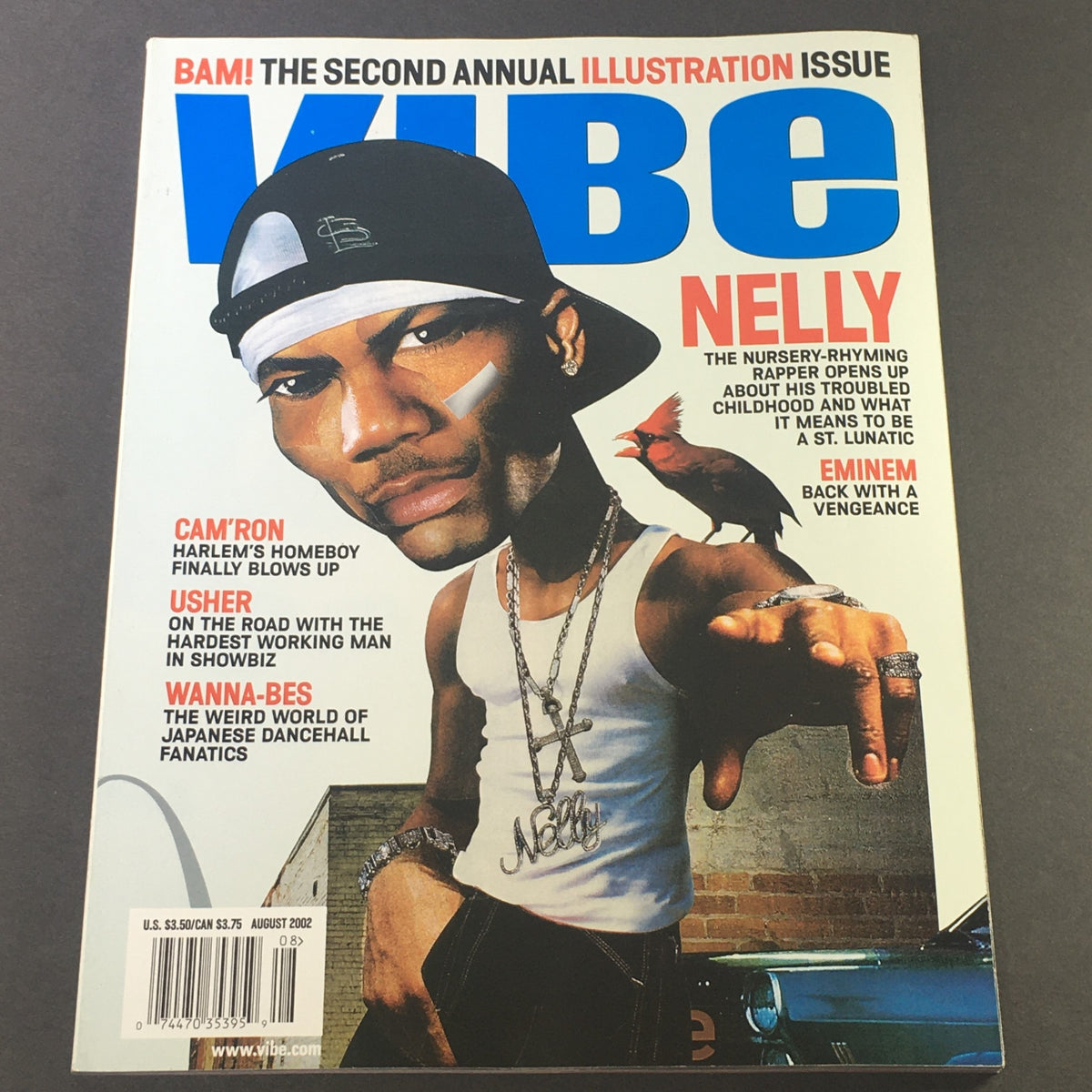 Cover of Vibe Magazine August 2002 featuring rapper Nelly, along with Cam'Ron and Usher. The cover highlights Nelly's artistic representation and promotes features about Eminem and dancehall fanatics.