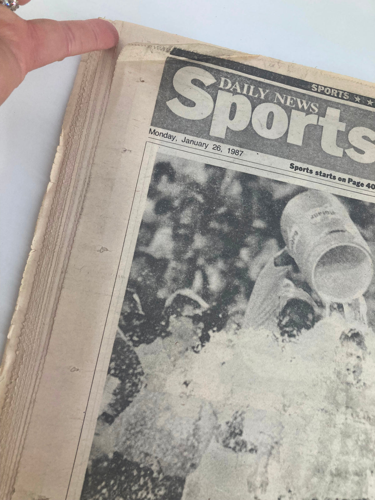 Close-up view of the January 26, 1987 VTG Daily News Newspaper depicting Coach Bill Parcells being celebrated by players after Super Bowl XXI, highlighting the newspaper's condition and vintage appeal.
