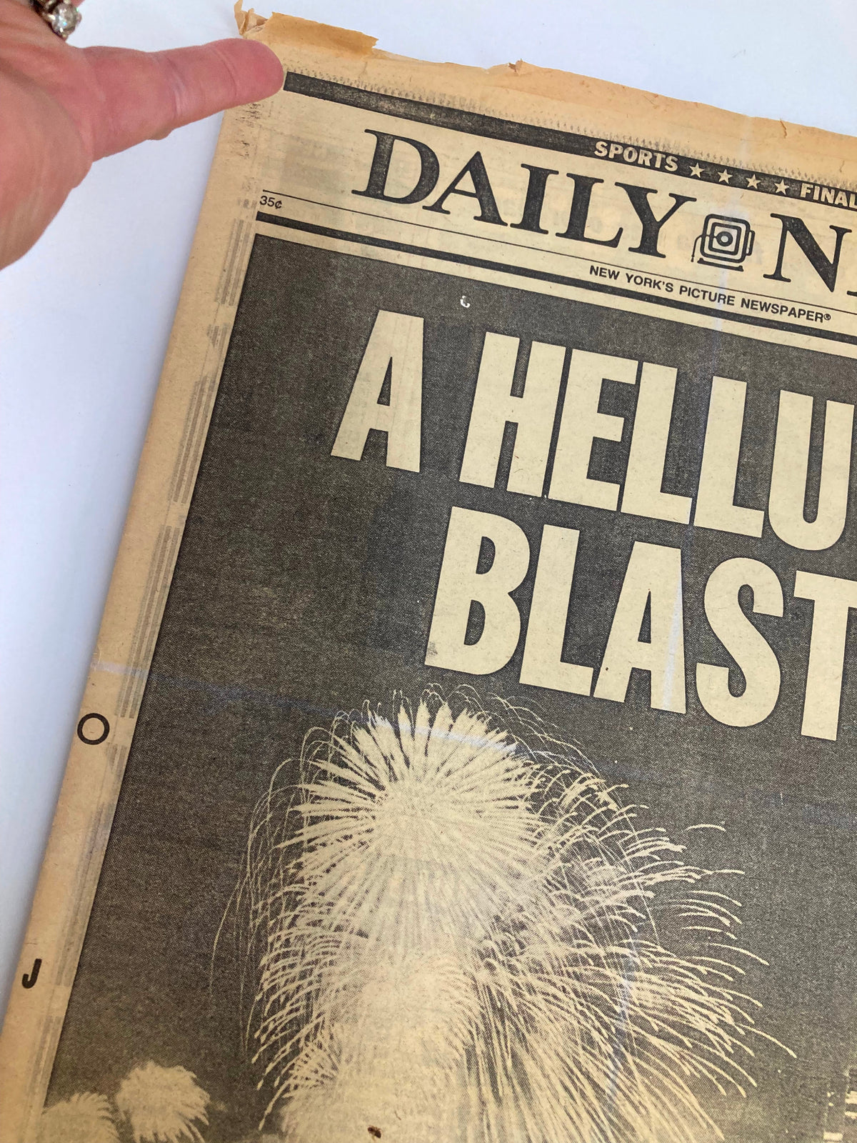Close-up of VTG Daily News Newspaper July 5 1986 showing the headline 'A Helluva Blast' with a hand pointing at the top.