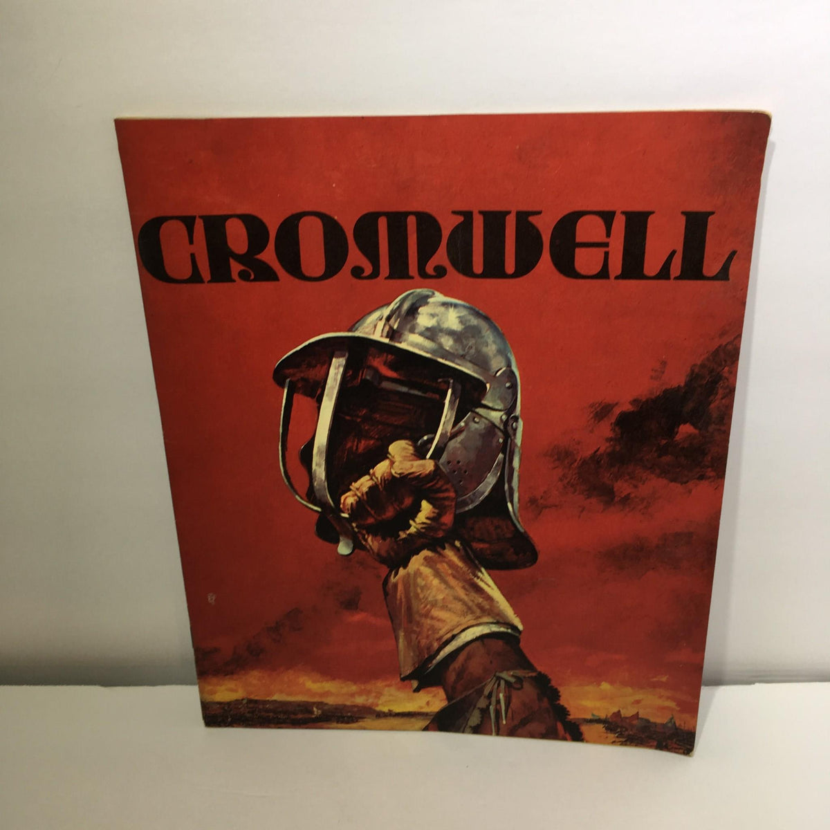 Cover of Cromwell Magazine by Dr. Maurice Ashley featuring a striking image of a soldier in a helmet against a vibrant orange background, symbolizing the historical themes explored in the magazine.