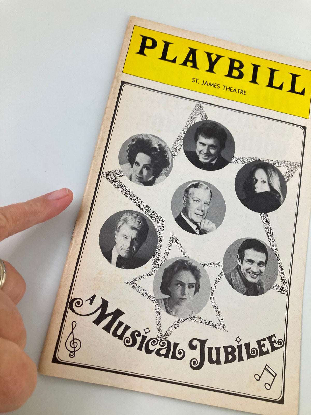 Close-up view of the 1975 Playbill from St. James Theatre for the musical Jubilee, highlighting performers with a finger pointing at the cover.