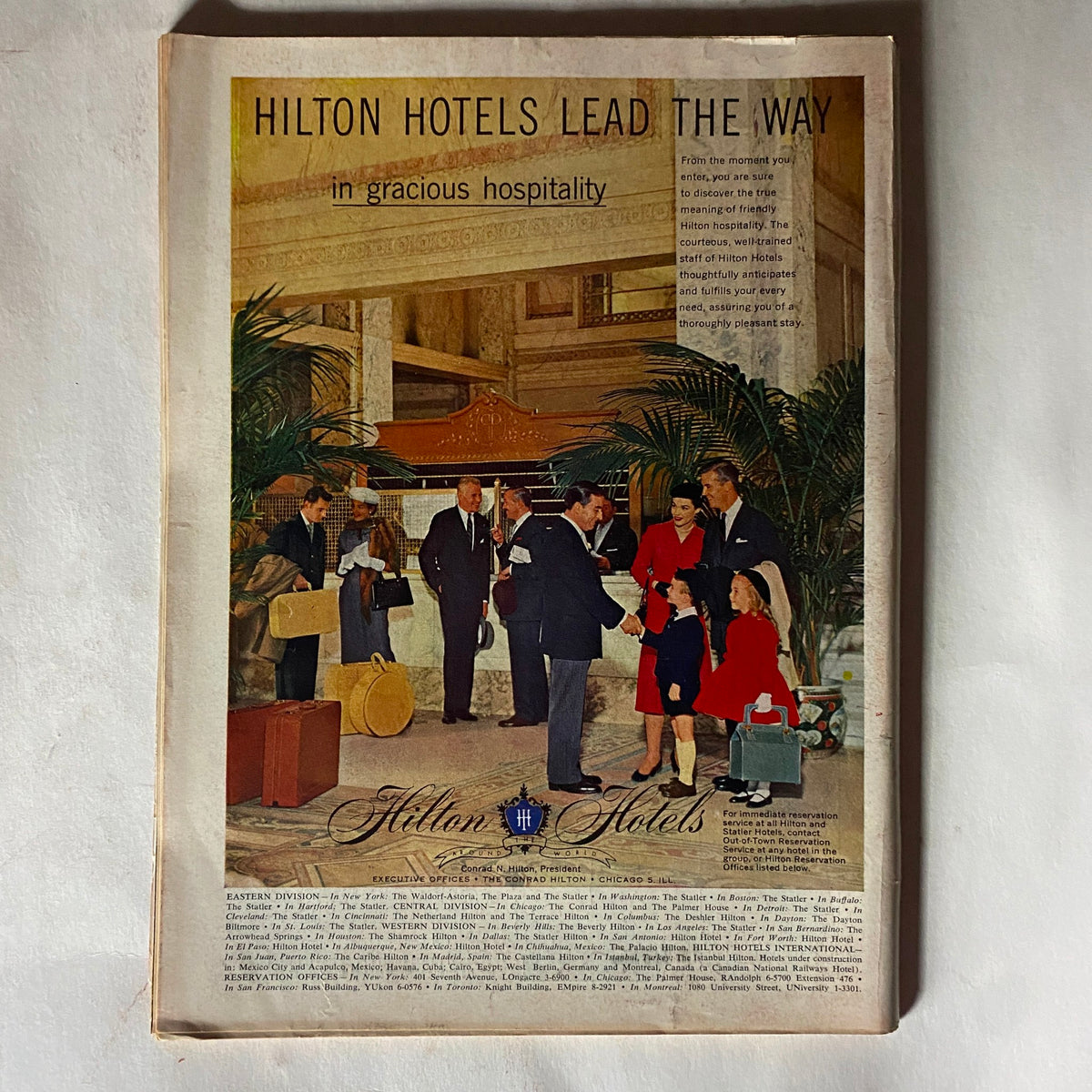Advertisement for Hilton Hotels from the vintage Time Magazine issue dated October 29, 1956, showcasing gracious hospitality in a luxurious hotel setting.