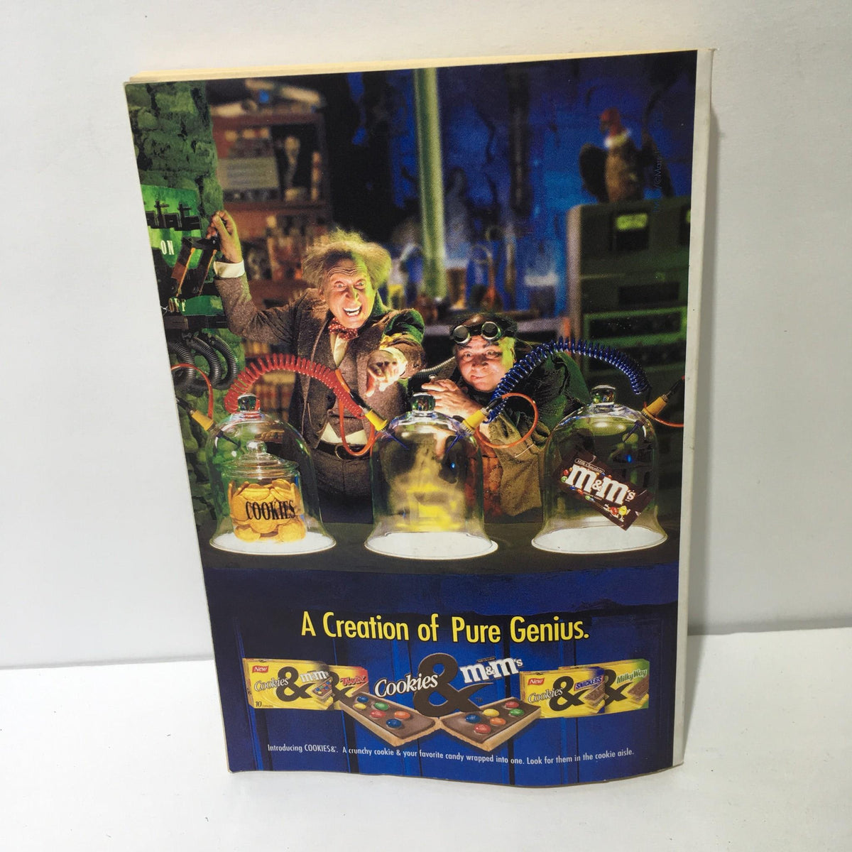Promotional advertisement featuring animated characters with cookies and M&M's, titled 'A Creation of Pure Genius.'