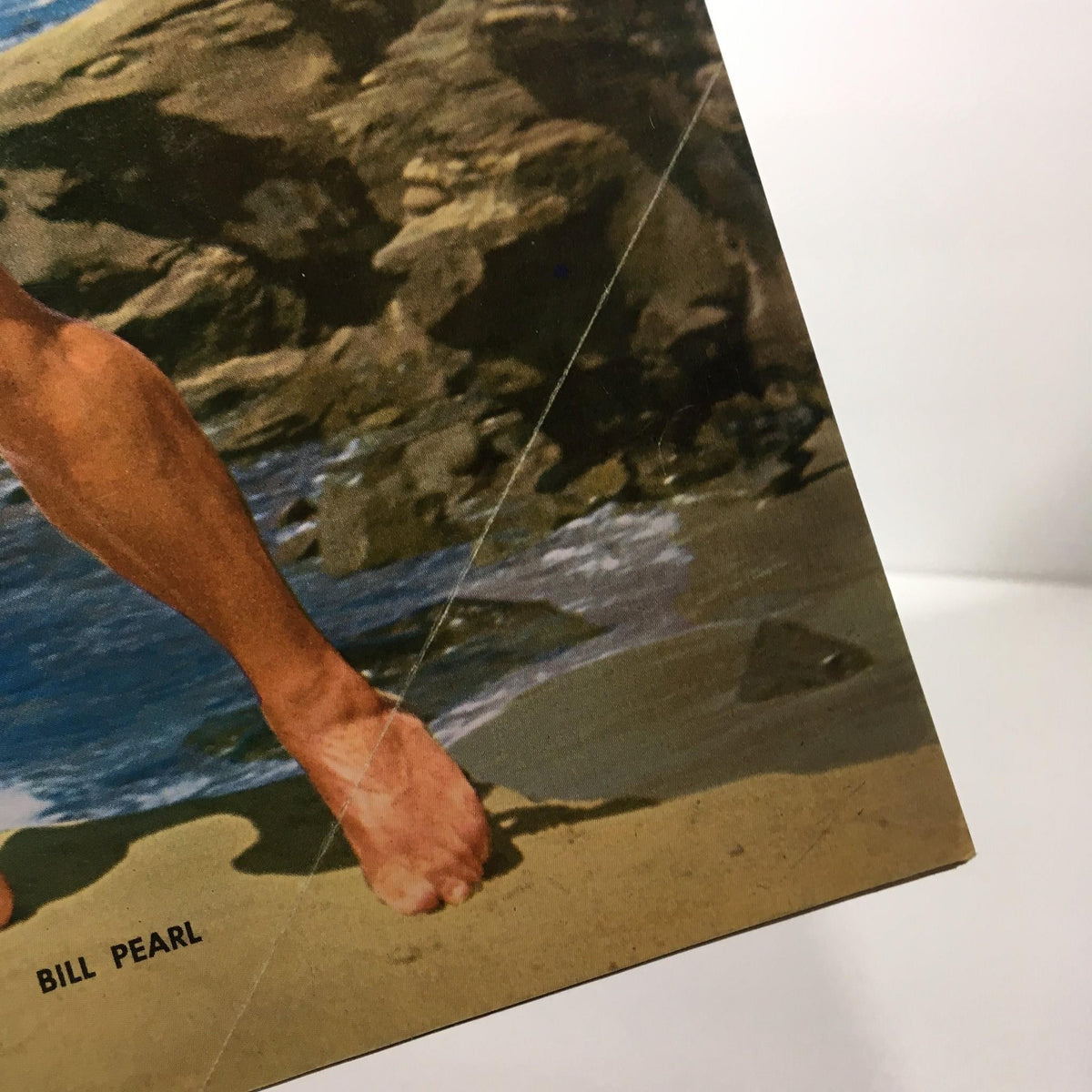 Close-up of a foot in the November 1969 Muscular Development Magazine showing 'Bill Pearl' written on the page.