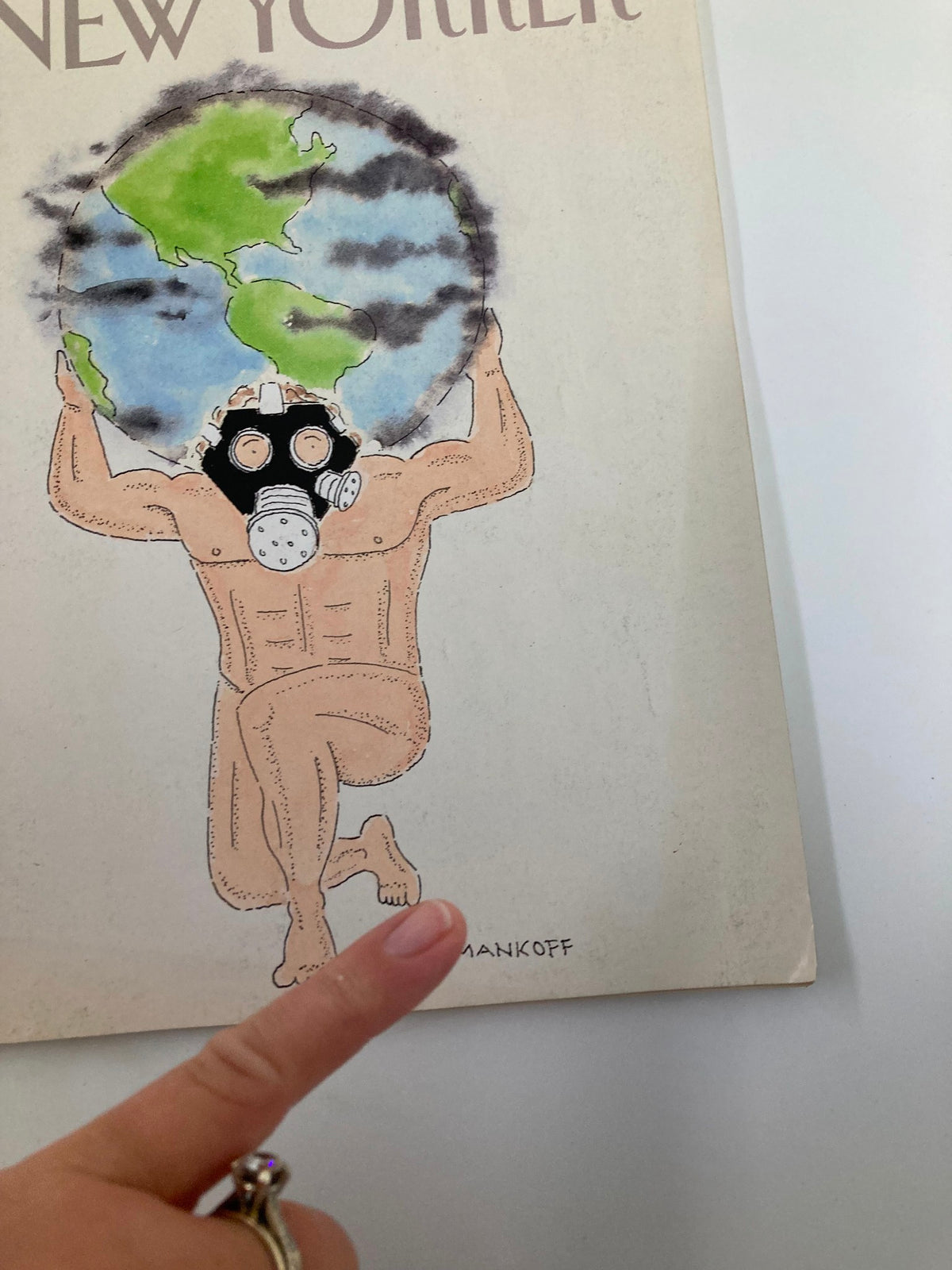 Close-up of the cover illustration from The New Yorker Full Magazine April 23 1990, 'Carrying The Earth' by Robert Mankoff, with a hand pointing at the artist's signature.
