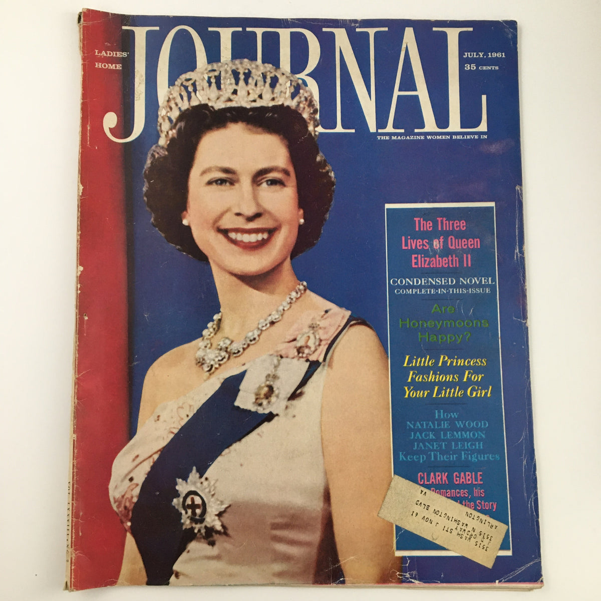 Cover of Ladies' Home Journal Magazine from July 1961 featuring the title 'The Three Lives of Queen Elizabeth II'. The magazine displays a portrait of Queen Elizabeth II with a crown and elegant attire, set in vibrant colors.