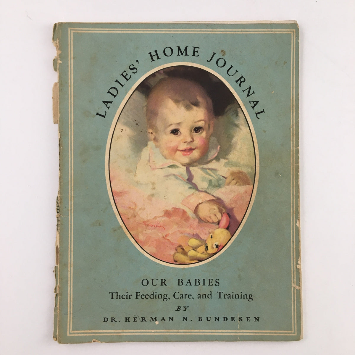 Cover of Ladies' Home Journal 'Our Babies Their Feeding, Care and Training' by Dr. Herman, featuring a portrait of a smiling infant with a teddy bear.