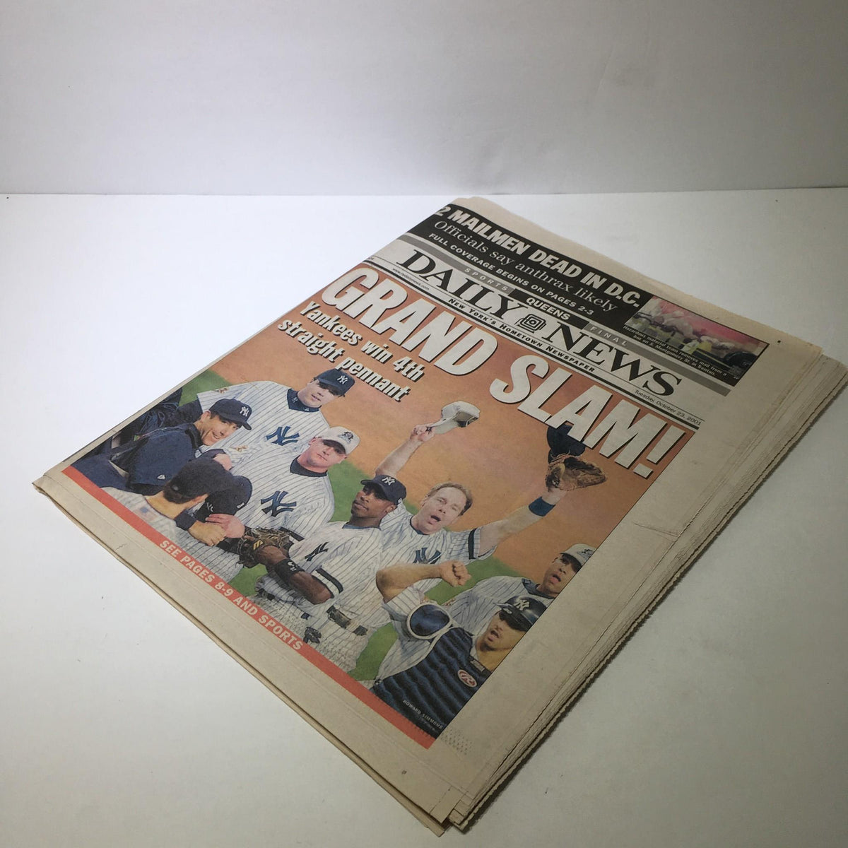 Overview of the NY Daily News front page featuring the vibrant headline 'Grand Slam! Yankees Win 4th Straight Pennant' with images of celebratory Yankees players.