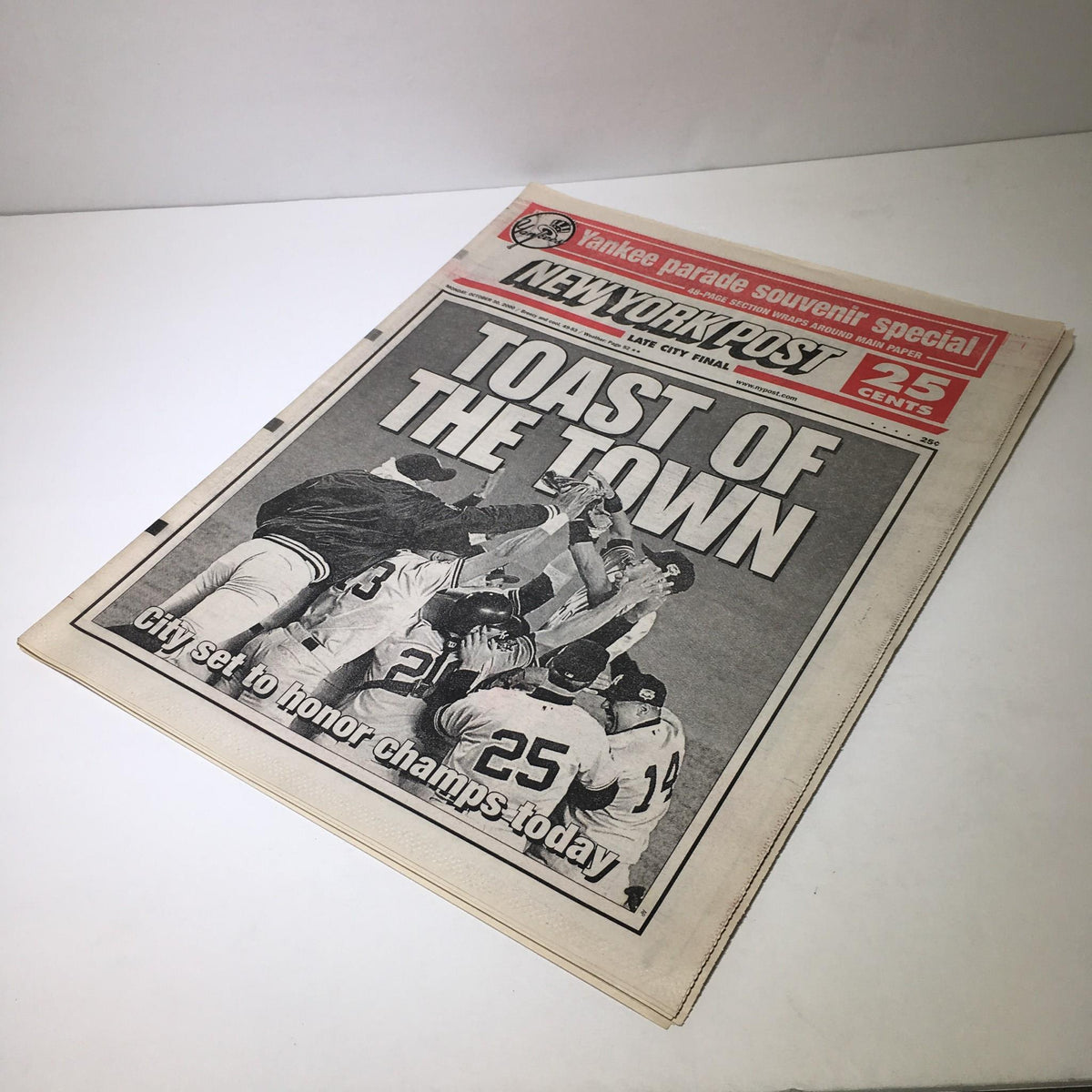Another view of the New York Post with the headline 'Toast of the Town' from October 30, 2000. The image depicts a jubilant scene of team members celebrating a championship victory.