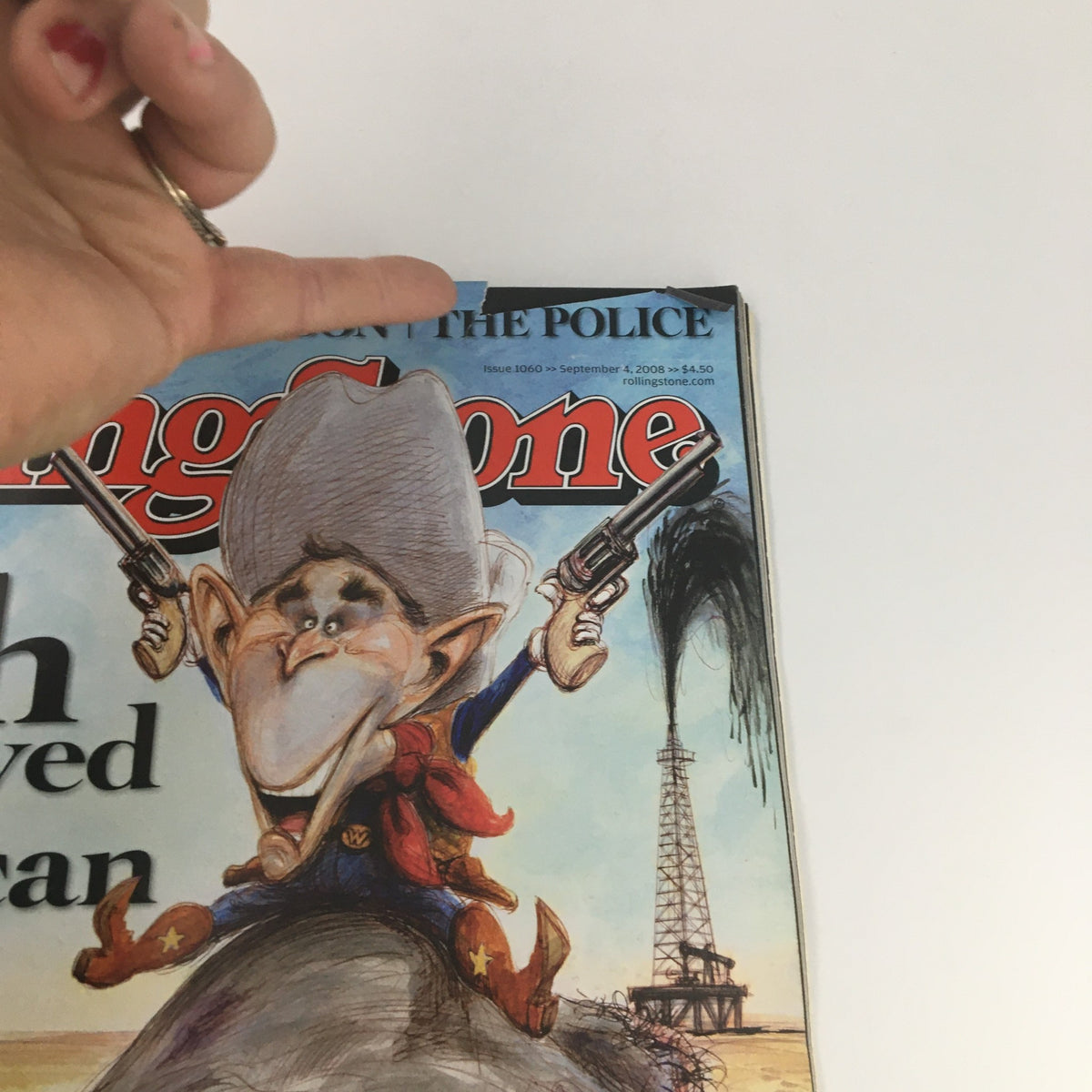 Close-up view of the Rolling Stone Magazine cover dated September 4, 2008, issue #1060, highlighting the caricature of George W. Bush with a humorous expression, holding guns with a glimpse of the oil rig in the background.