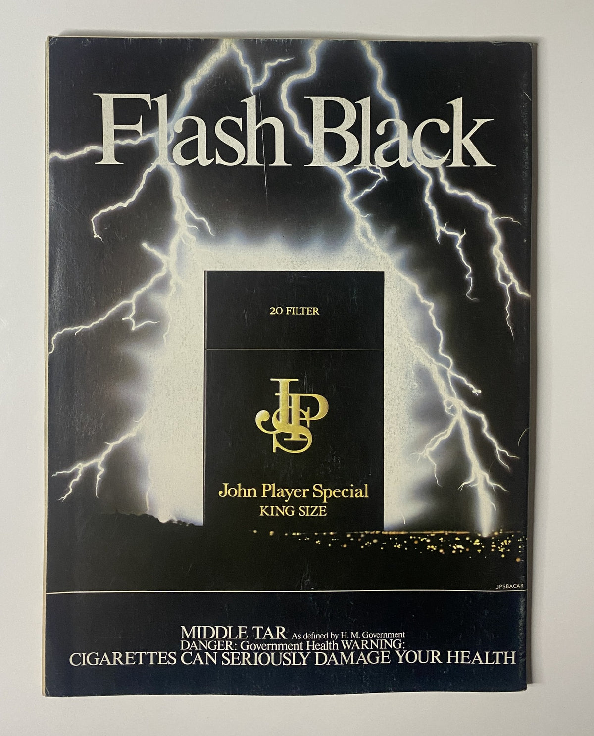 Cover of Flash Black cigarette package featuring John Player Special branding and health warnings, produced by H.M. Government, presented in the context of the CAR Magazine January 1984 issue.