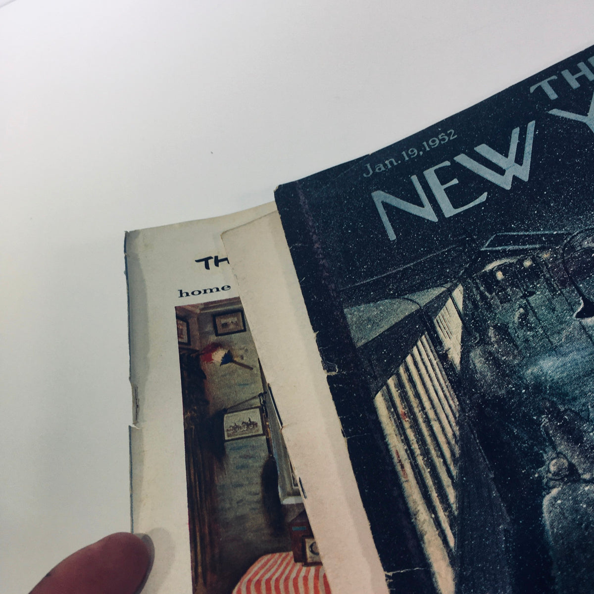 Image of the The New Yorker: January 19 1952 magazine partially opened, showing the interior edge and revealing more wear on the edges, emphasizing its vintage character.