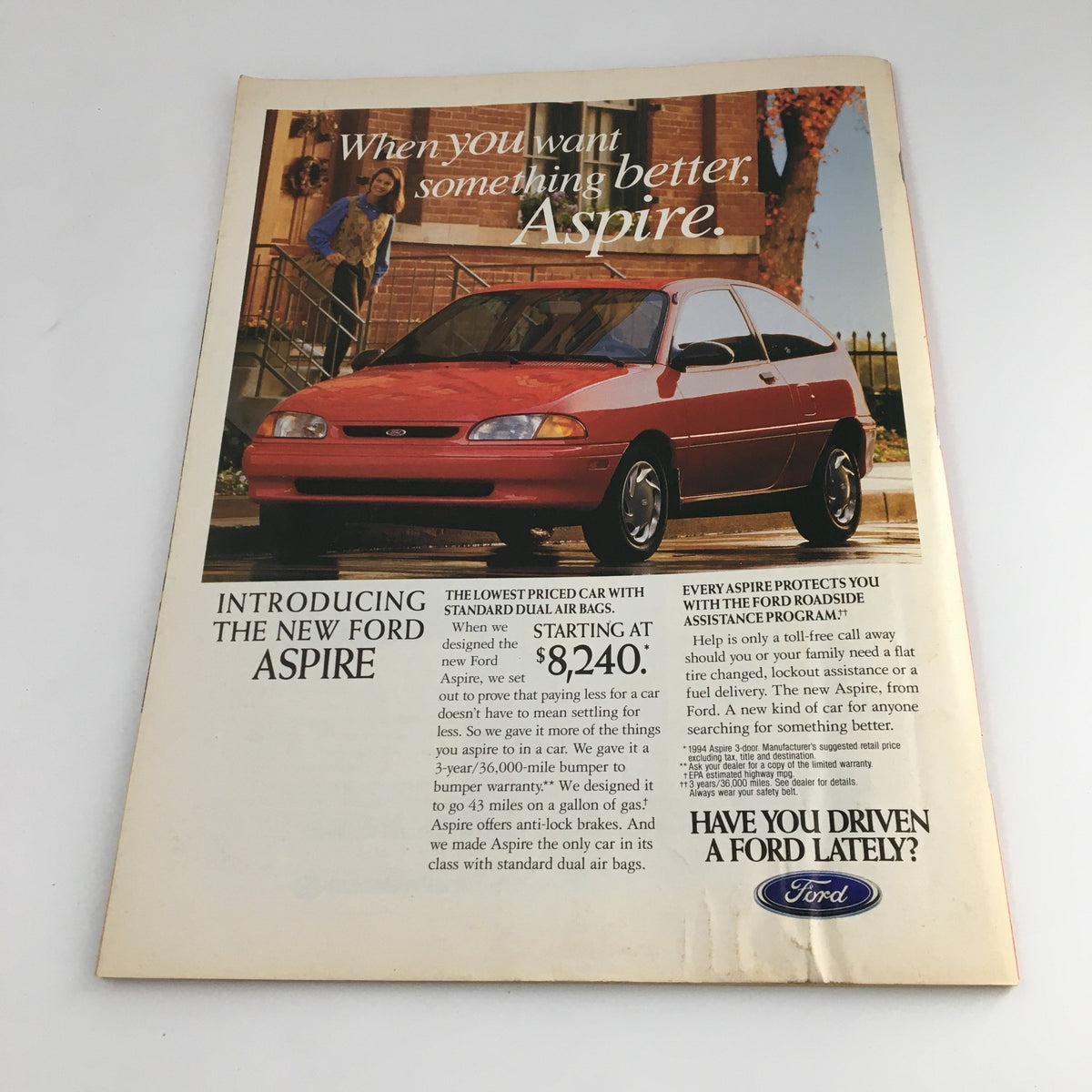 Advertisement page introducing the new Ford Aspire from a 1994 issue, featuring the car with a woman standing by it and showcasing starting price.