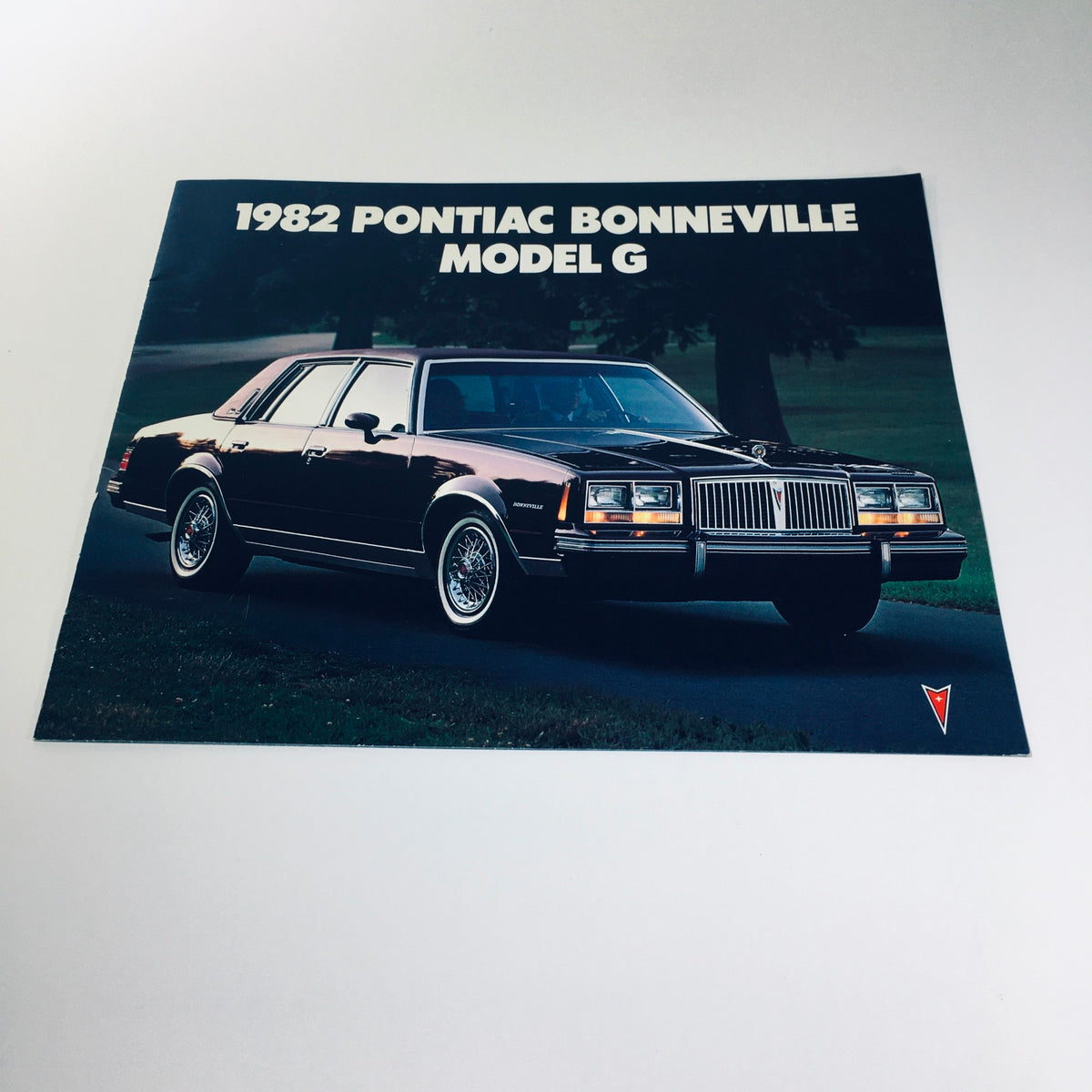 1982 Pontiac Bonneville Model G Brougham 4-Door Sedan Car Sales Brochure featuring the exterior view of the car parked on a scenic road.