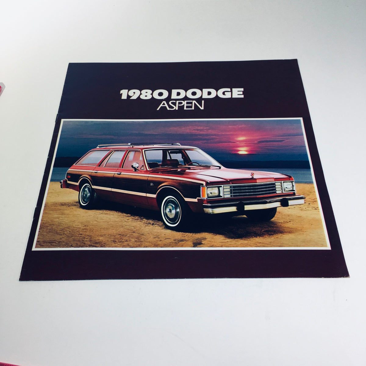 1980 Dodge Aspen Coupe Optional T-Bar Roof Compact Car Sale Brochure featuring an exterior shot of the car on the beach at sunset.