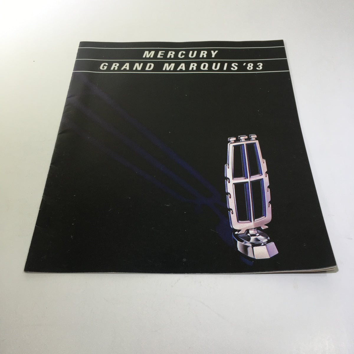 1983 Mercury Grand Marquis Class Act Fuel-Injected 5.0 L V-8 Engine Car Brochure cover featuring a sleek design with a stylized illustration of a vehicle emblem, published in 1983.