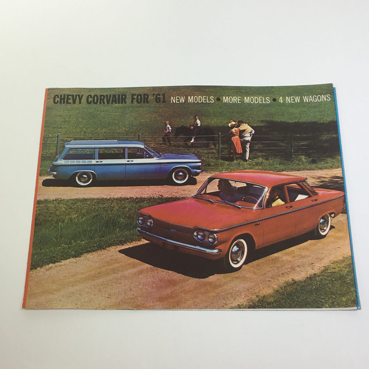 1961 Chevy Corvair 500 Car Sale Catalog featuring a bright red sedan alongside a blue wagon on a scenic road, showcasing the new models available.