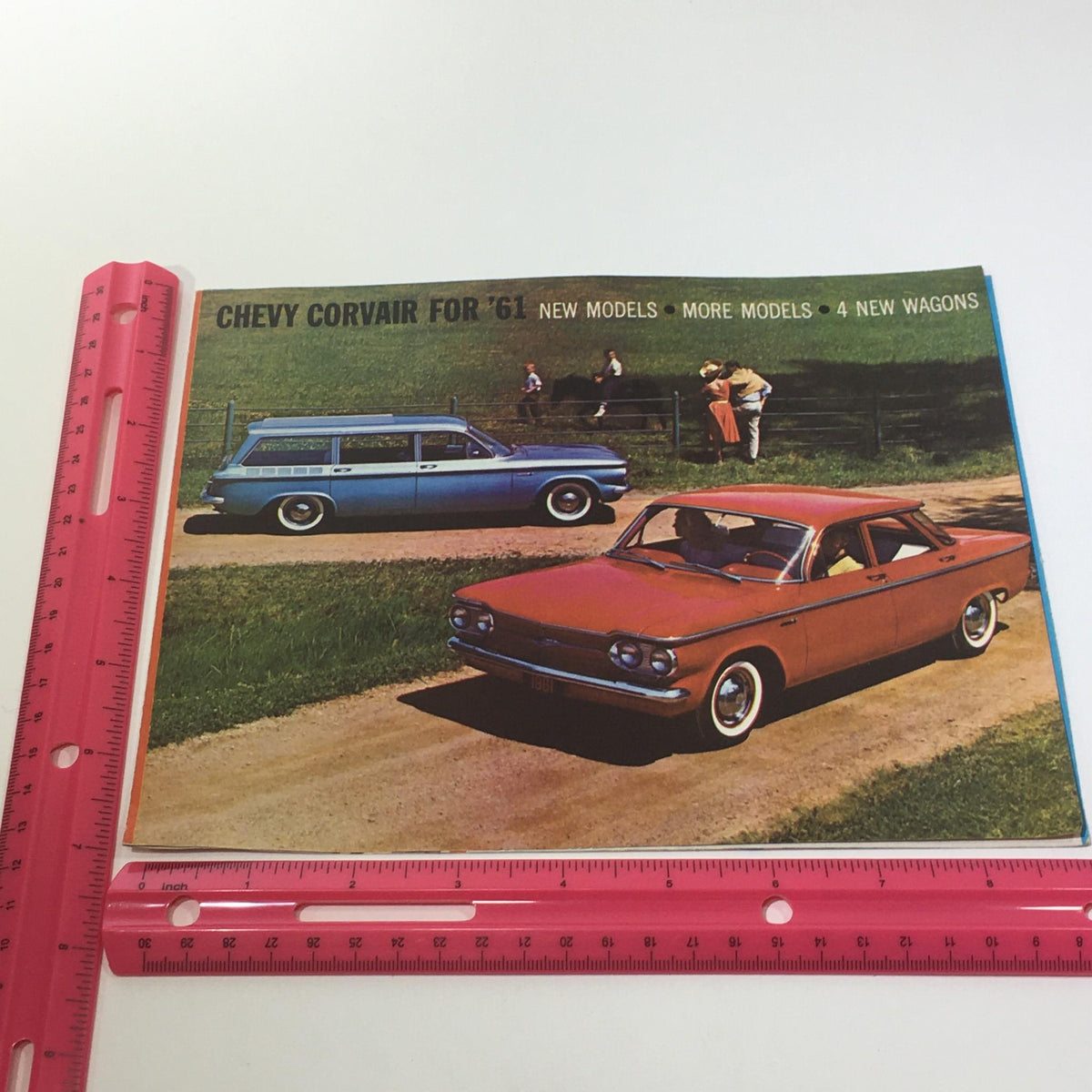 Cover image of the 1961 Chevy Corvair 500 Car Sale Catalog demonstrating a captivating view of a red sedan and a blue wagon on a country road.