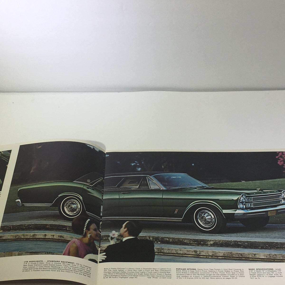 Inside view of the 1966 Ford 200-HP V-8 Engine Cruise-O-Matic Drive Die-Cast Grill Car Catalog showcasing a classic green Ford car parked by a staircase.
