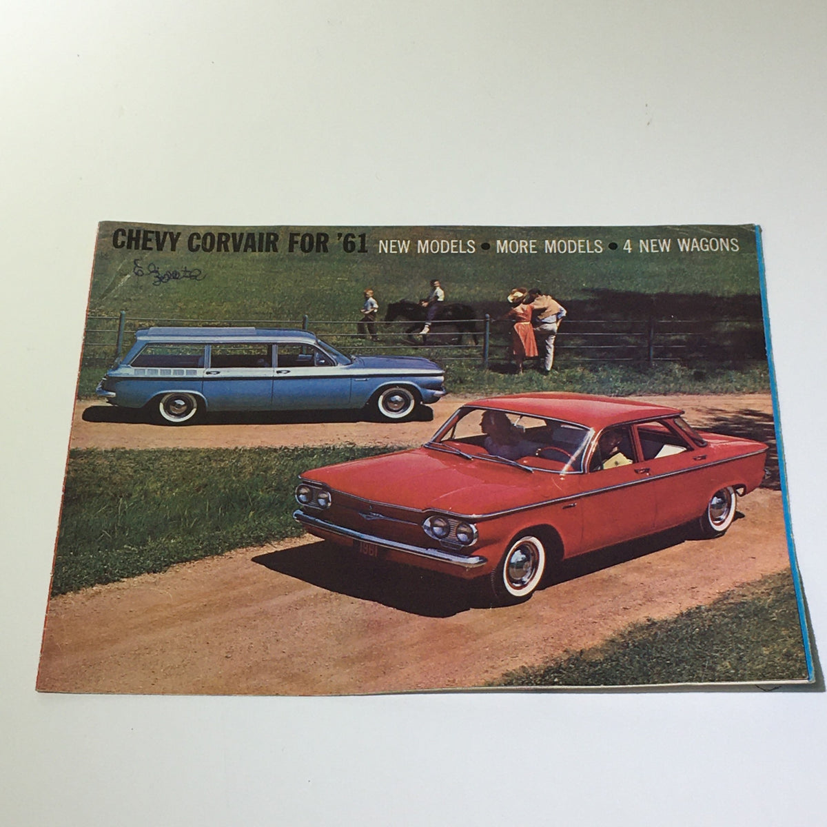 Cover of 1961 Chevy Corvair 500 brochure showcasing a red Chevy Corvair and blue Corvair model on a green field, highlighting new models and features.