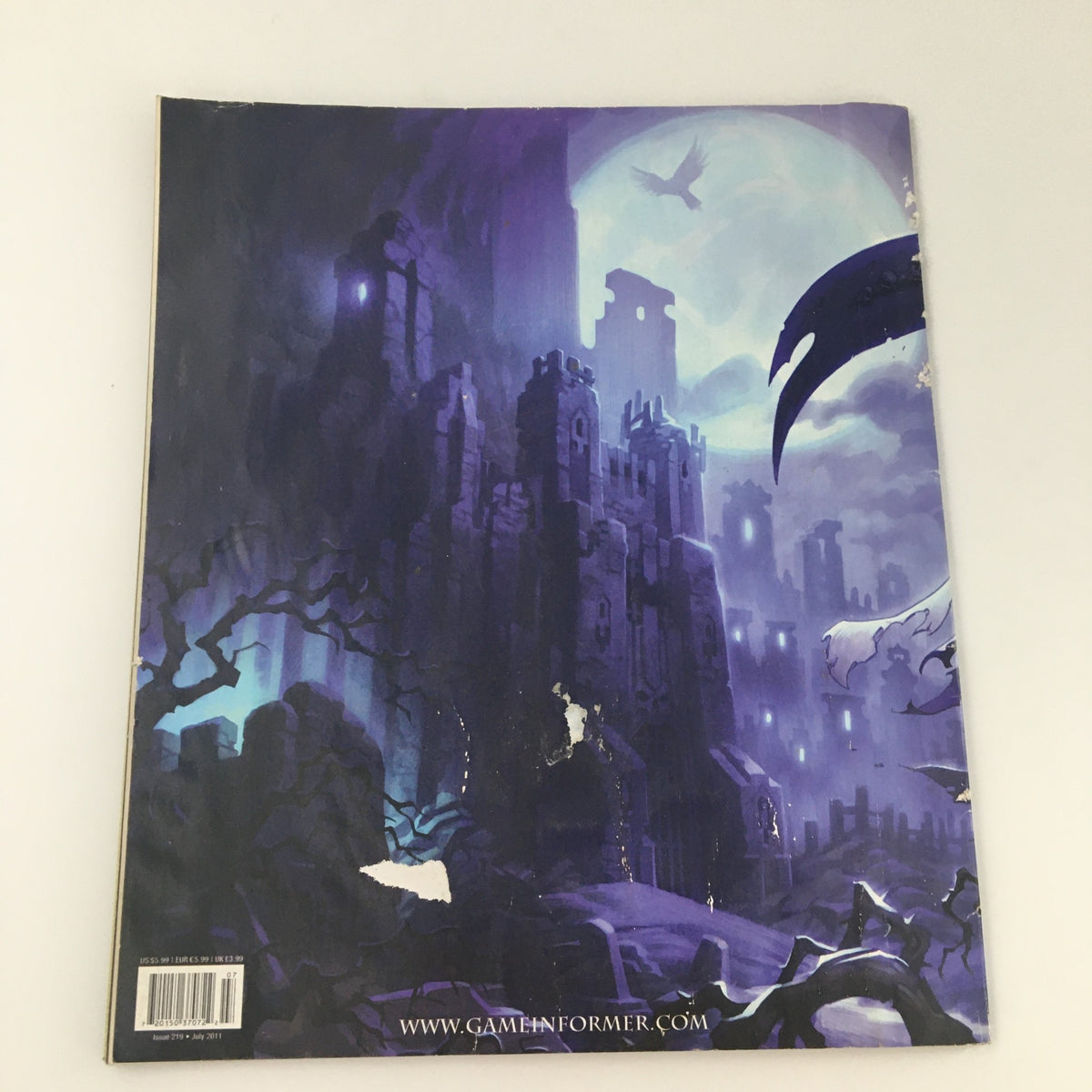 Back cover of the Game Informer Magazine July 2011 Issue 219 featuring a dark, atmospheric illustration of a castle and a raven, representing the themes of the Darksiders II game.