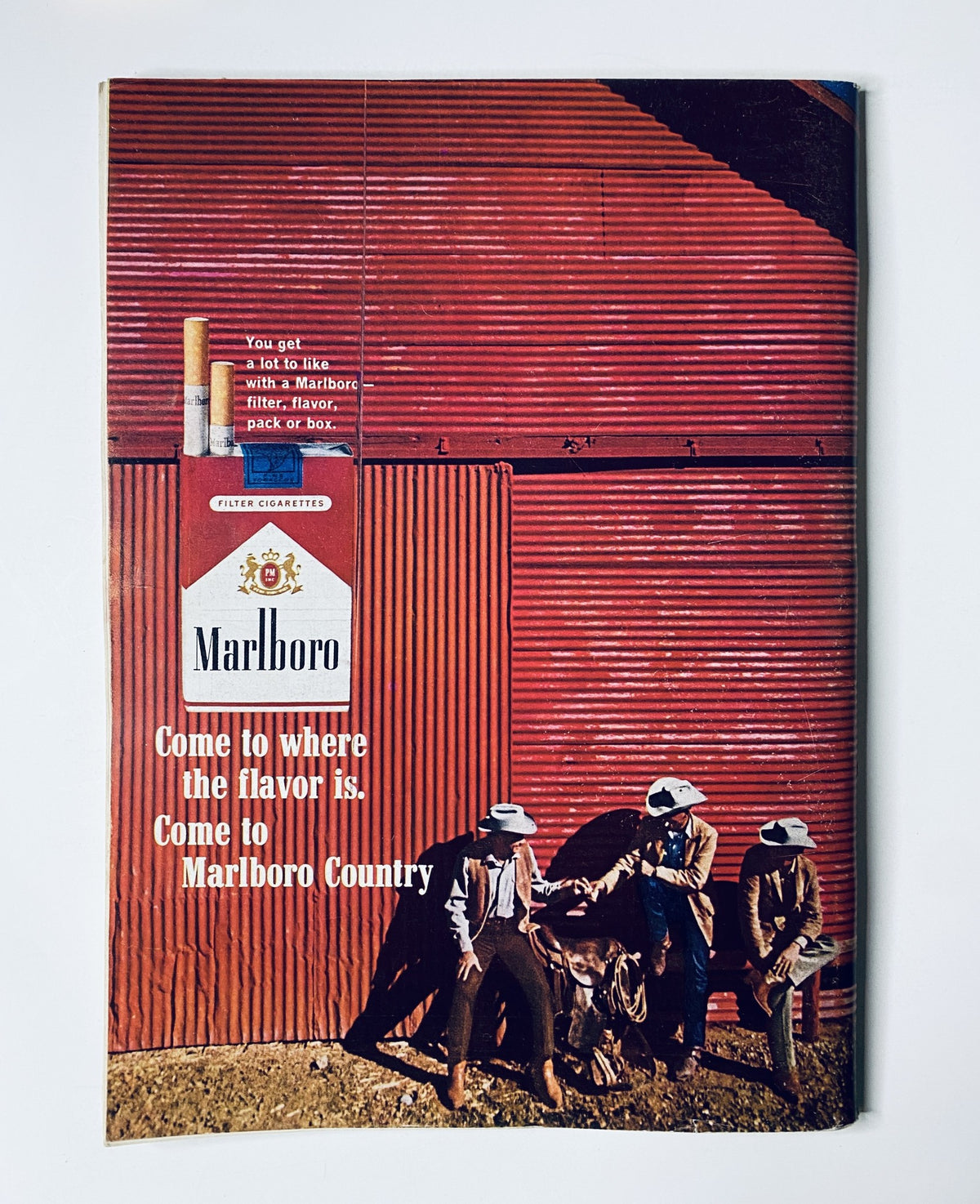 Marlboro advertisement from The New Yorker Magazine May 15, 1965, showcasing a rural scene with individuals and the tagline 'Come to where the flavor is. Come to Marlboro Country'.