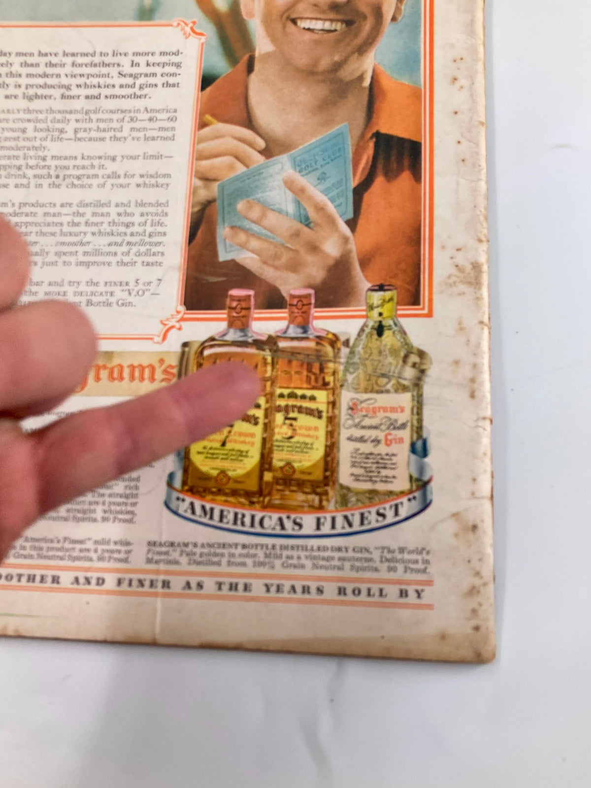 Back cover detail of VTG Liberty Magazine, October 21, 1939, featuring a smiling man holding a card with bottles of Seagram's whisky in the background.