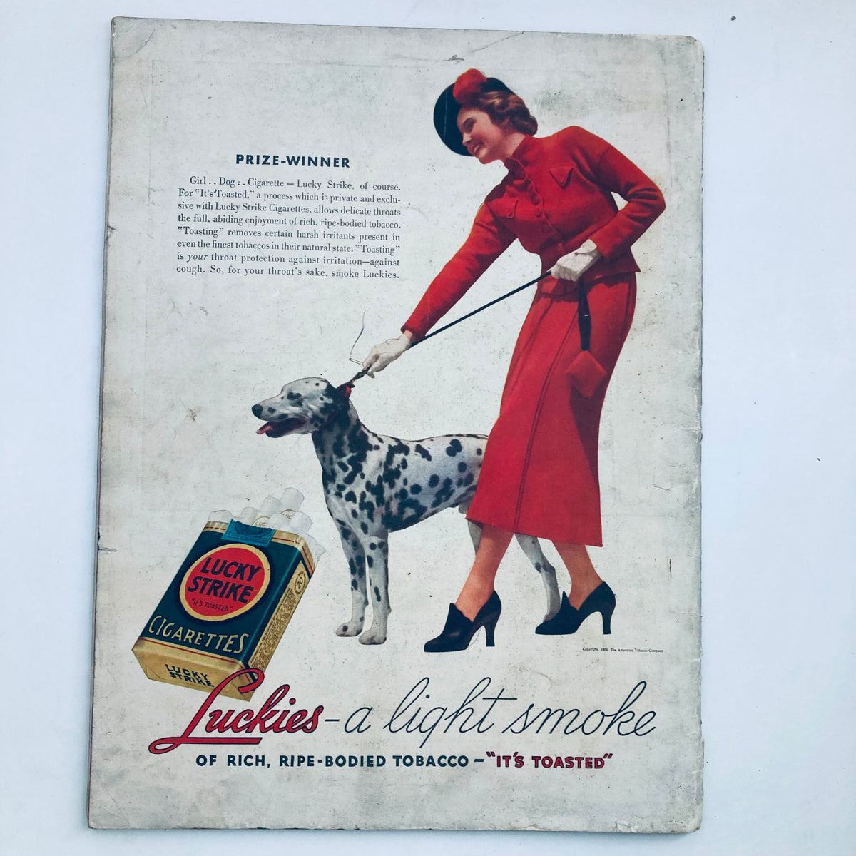 Vintage advertisement featuring a woman in a red outfit walking a Dalmatian dog, associated with Lucky Strike cigarettes, from the first issue of VTG Life Magazine, November 23, 1936, Volume 1, No. 1.