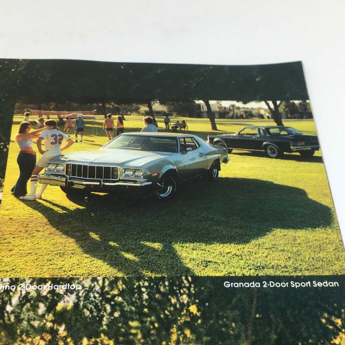 Vintage Free Wheelin' Mustang II MPG 2+2 Stallion - 1965 Shelby Cobra Car Brochure showing the Granada 2-Door Sport Sedan amidst a vibrant outdoor gathering.