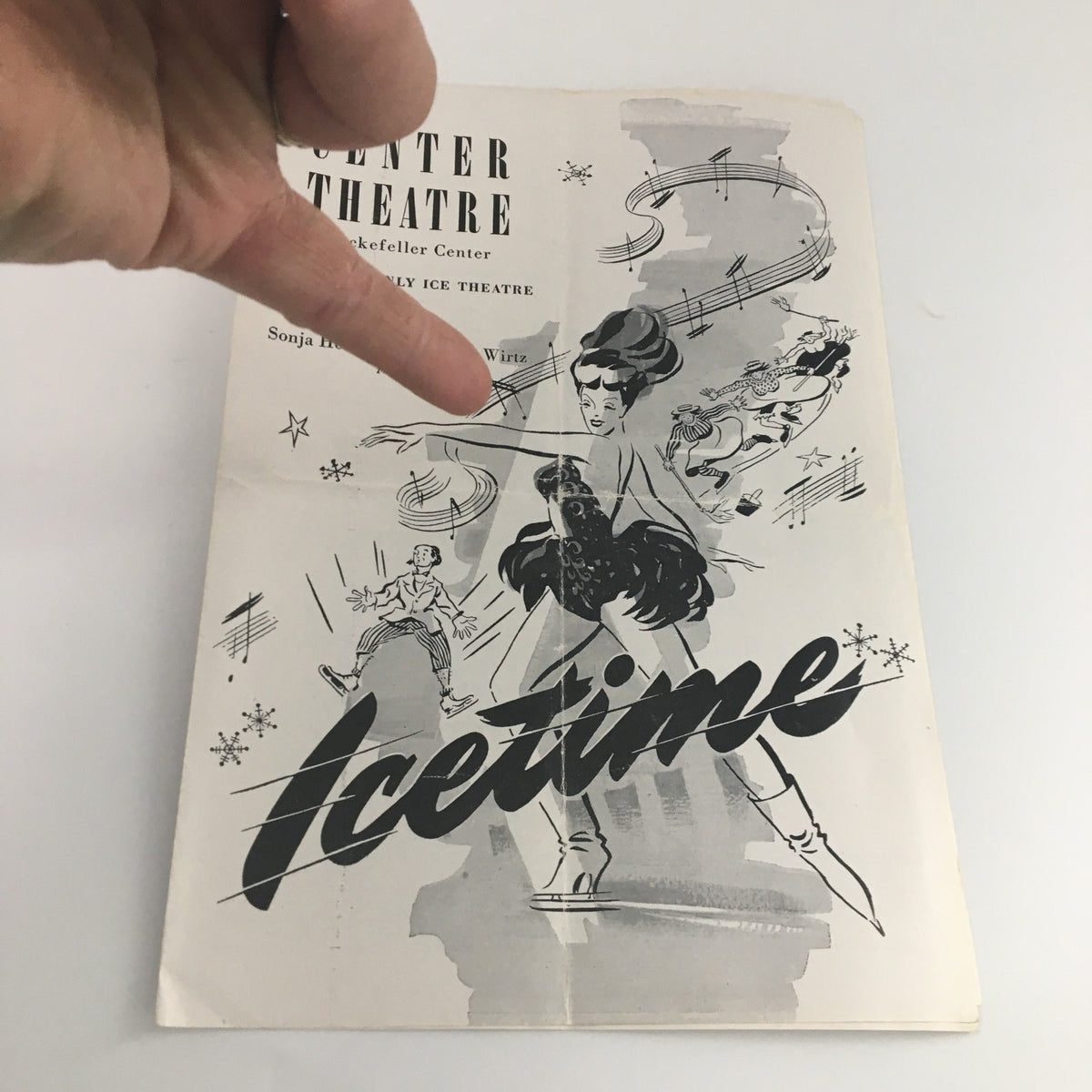 1946 Center Theatre Rockefeller Center 'Icetime' program with a hand pointing at the artwork, highlighting the vibrant illustration and the title of the show.
