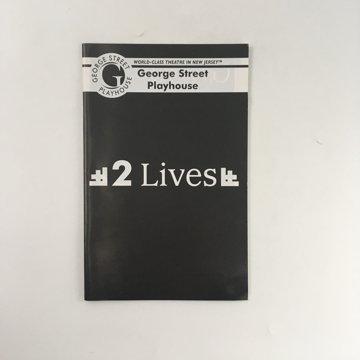 Cover of the playbook '2 Lives' by Arthur Laurents, presented by the George Street Playhouse, featuring a minimalist design with large text on a black background.