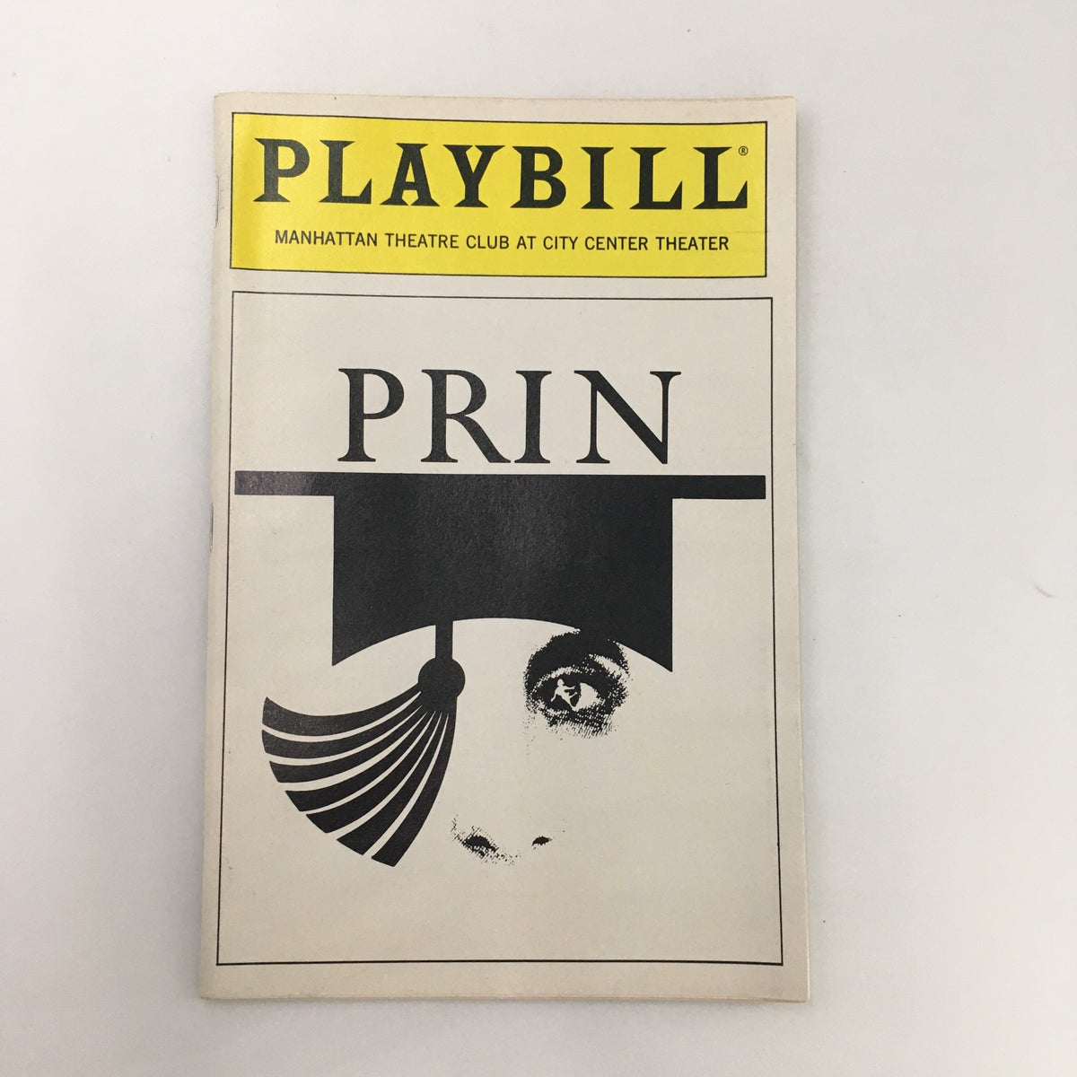 1990 Playbill for 'Prin' by Andrew Davies from Manhattan Theatre Club at City Center Theater, featuring a minimalist design with a prominent eye and graduation cap illustration.