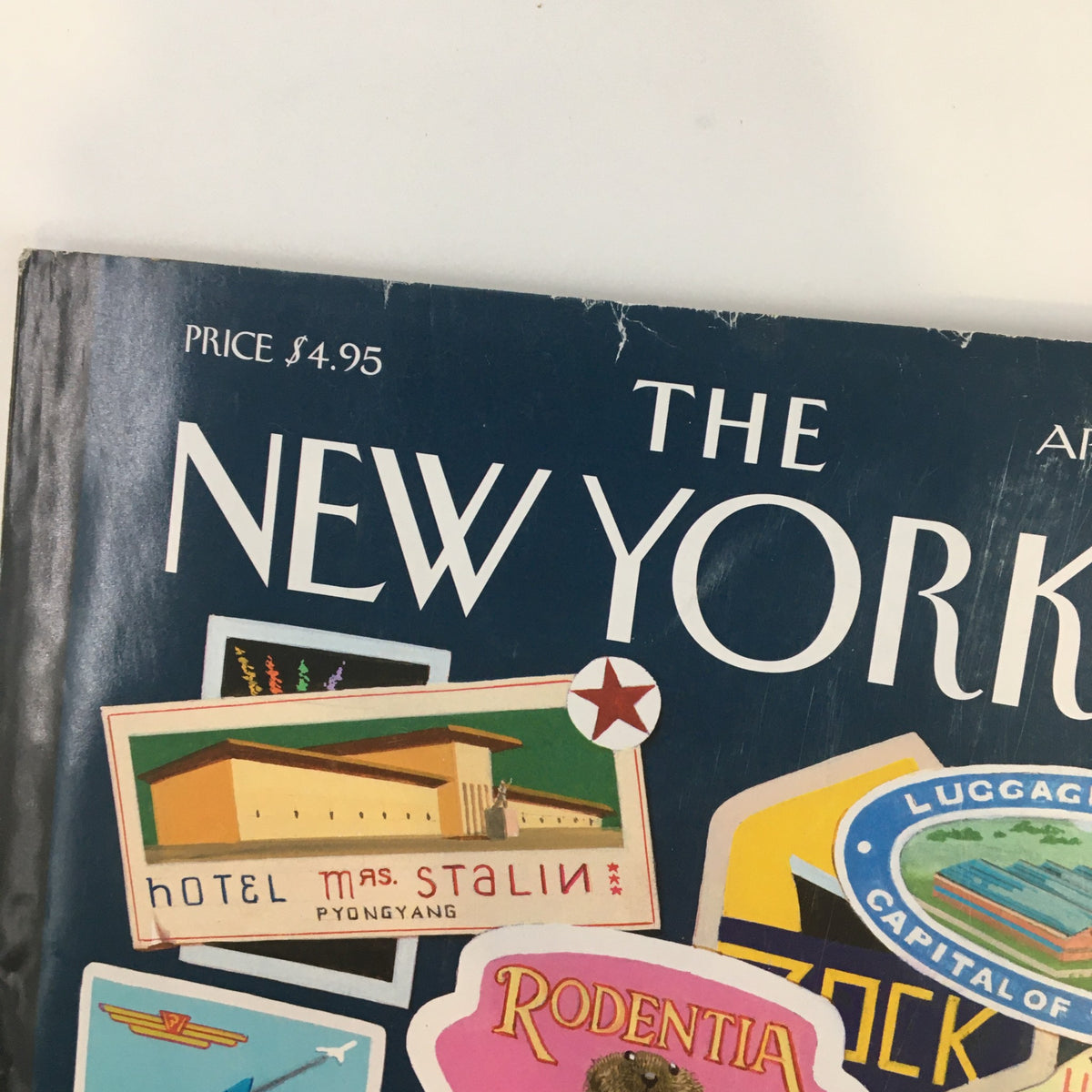Close-up view of The New Yorker Full Magazine April 18, 2005 cover showcasing the Hotel Mas Stalin and Rodentia travel stickers, emphasizing the Joys of Travel theme by Bruce McCall.