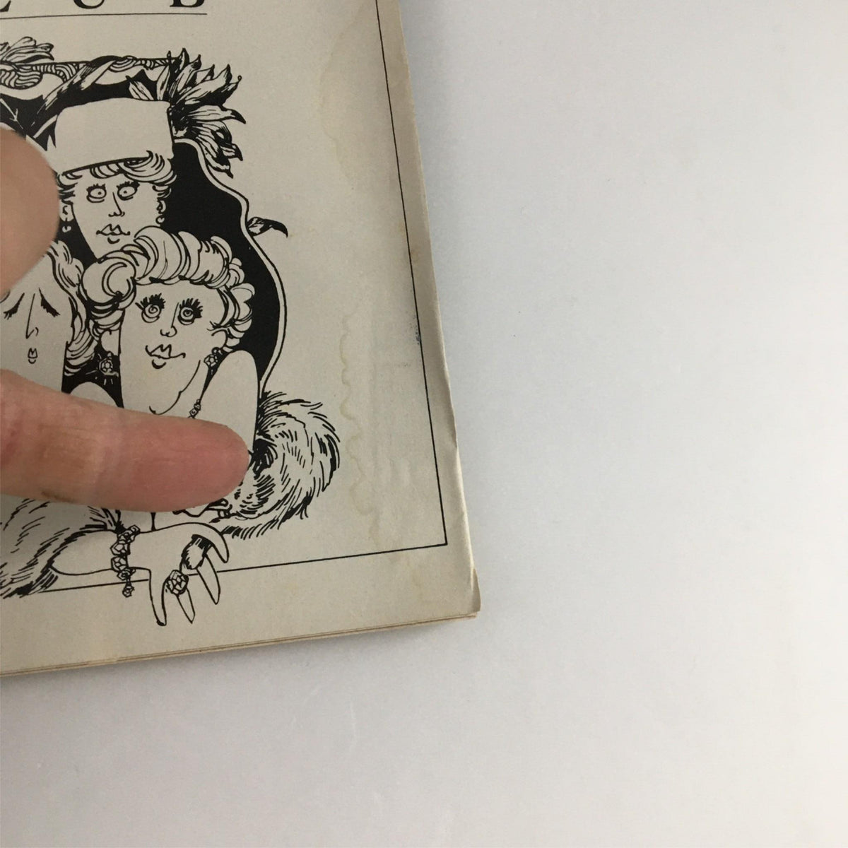 Close-up view of the cover of the 1990 Playbill for The Cemetery Club featuring artistic illustrations and hand on the edge.