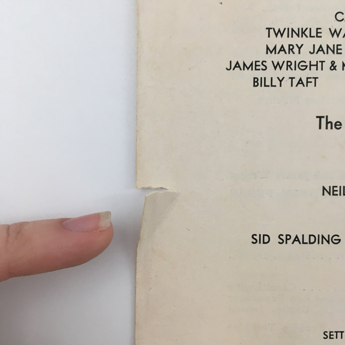Close-up of the 1943 Center Theatre 'Stars on Ice' booklet displaying a small tear and a finger for scale, emphasizing its vintage condition and charm.