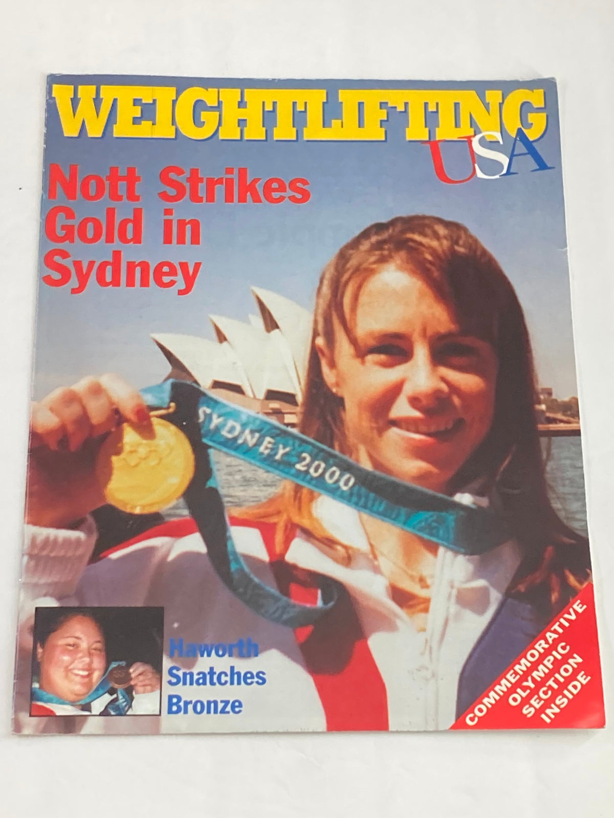 Cover of the Weightlifting USA Magazine 1998 featuring Tara Nott holding her Olympic Gold Medal won at the Sydney 2000 Olympics, celebrating her achievement in the 48kg weightlifting category.