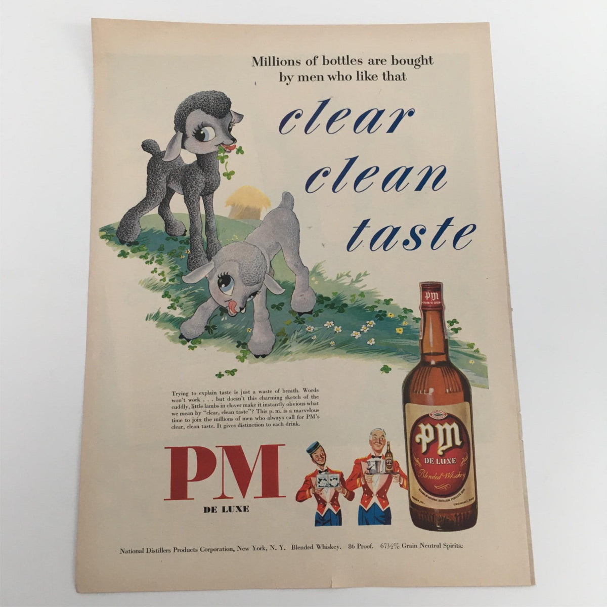 1950 PM De Luxe 86 Proof Blended Whiskey Vintage Print Ad featuring playful illustrations of two fuzzy dogs and a bottle of PM whiskey, showcasing nostalgic advertising artistry.