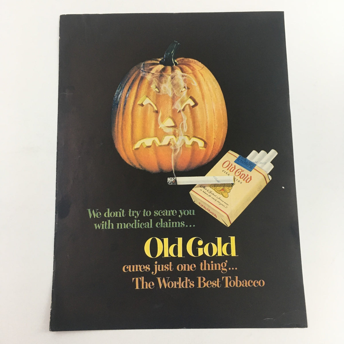 Vintage advertisement for Old Gold Cigarettes featuring a whimsical pumpkin graphic with a cigarette box, highlighting the tagline 'Old Gold cures just one thing... The World's Best Tobacco'.