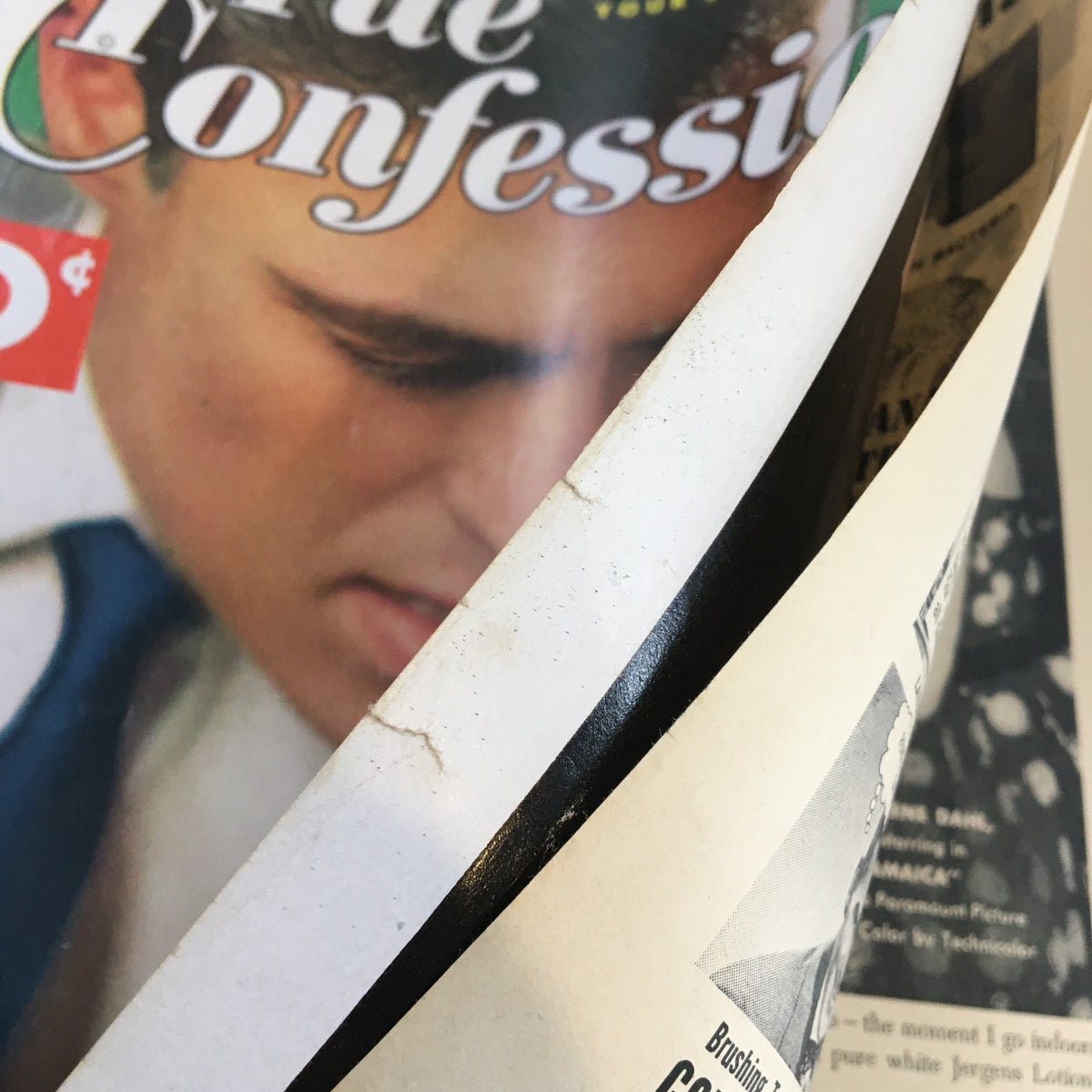 Side view of the True Confessions Magazine April 1953, revealing the cover design and a person's face partially visible on the front.