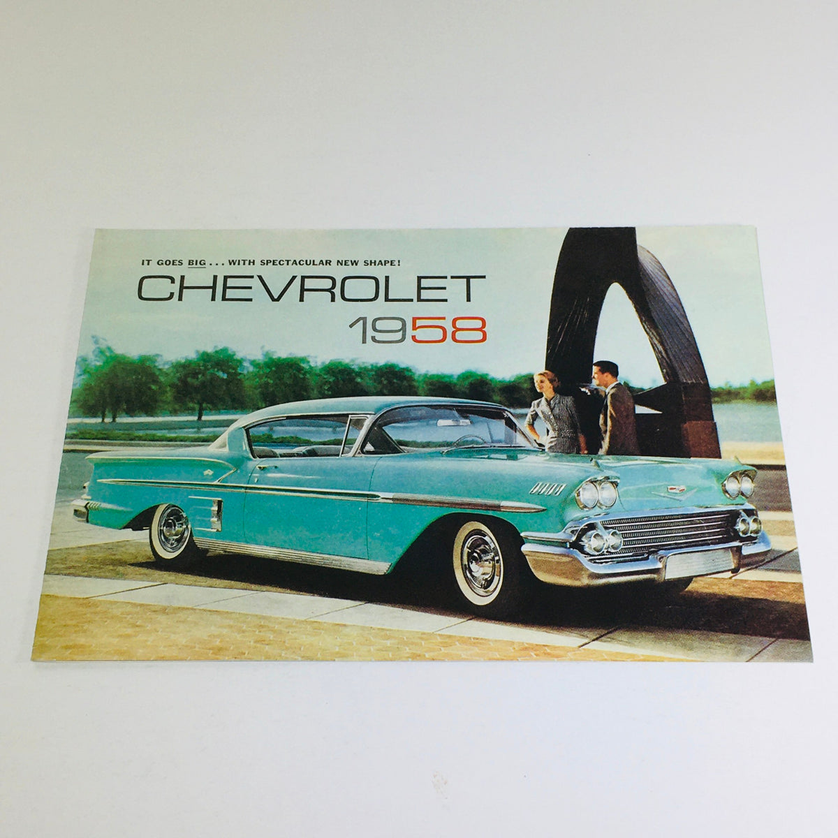 1958 Chevrolet Bel Air Corvette Dealership Car Auto Brochure Catalog showcasing a turquoise Chevrolet car with two people in front of it and artistic architecture in the background.